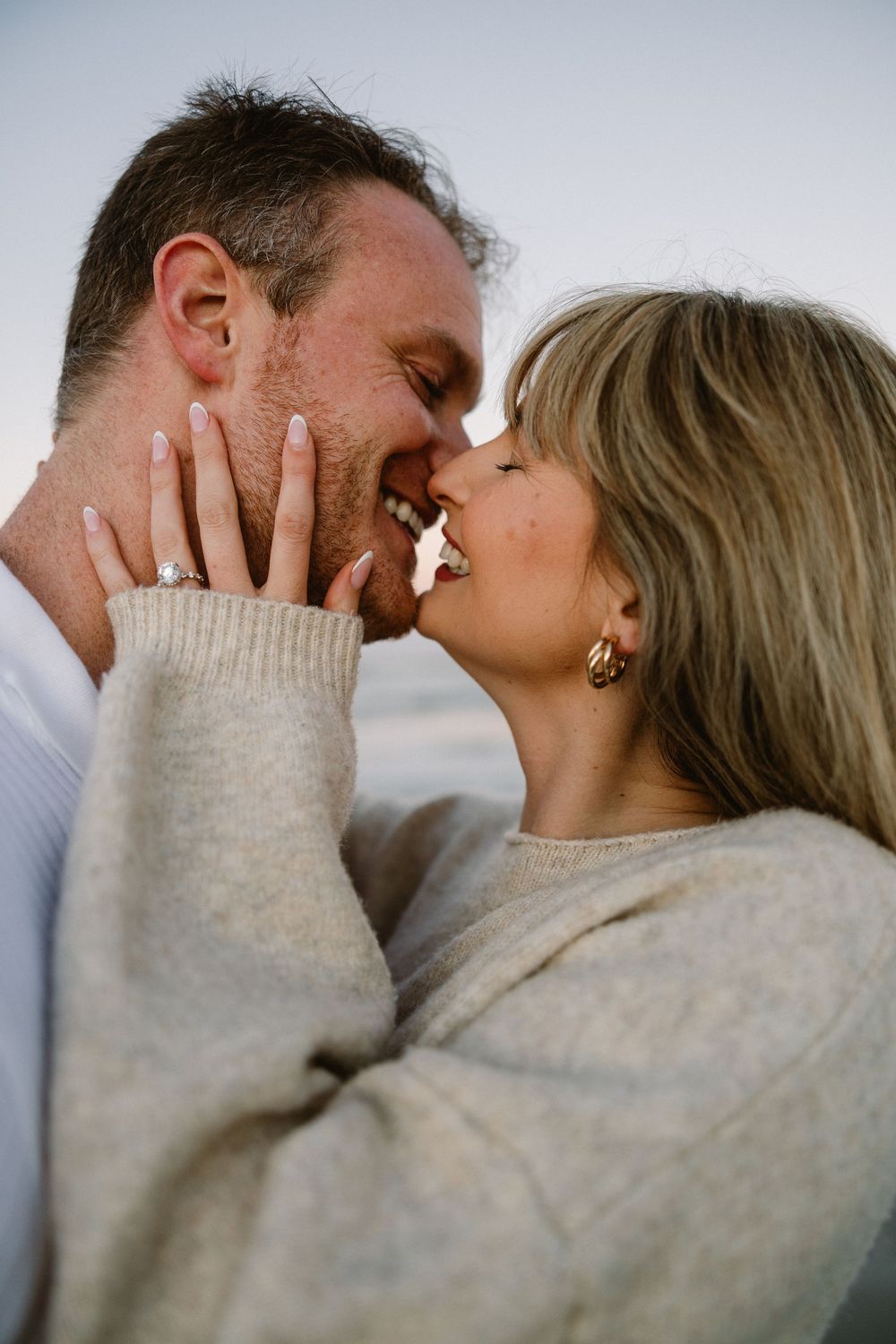 A couple shares an intimate close-up moment on the beach at sunset.