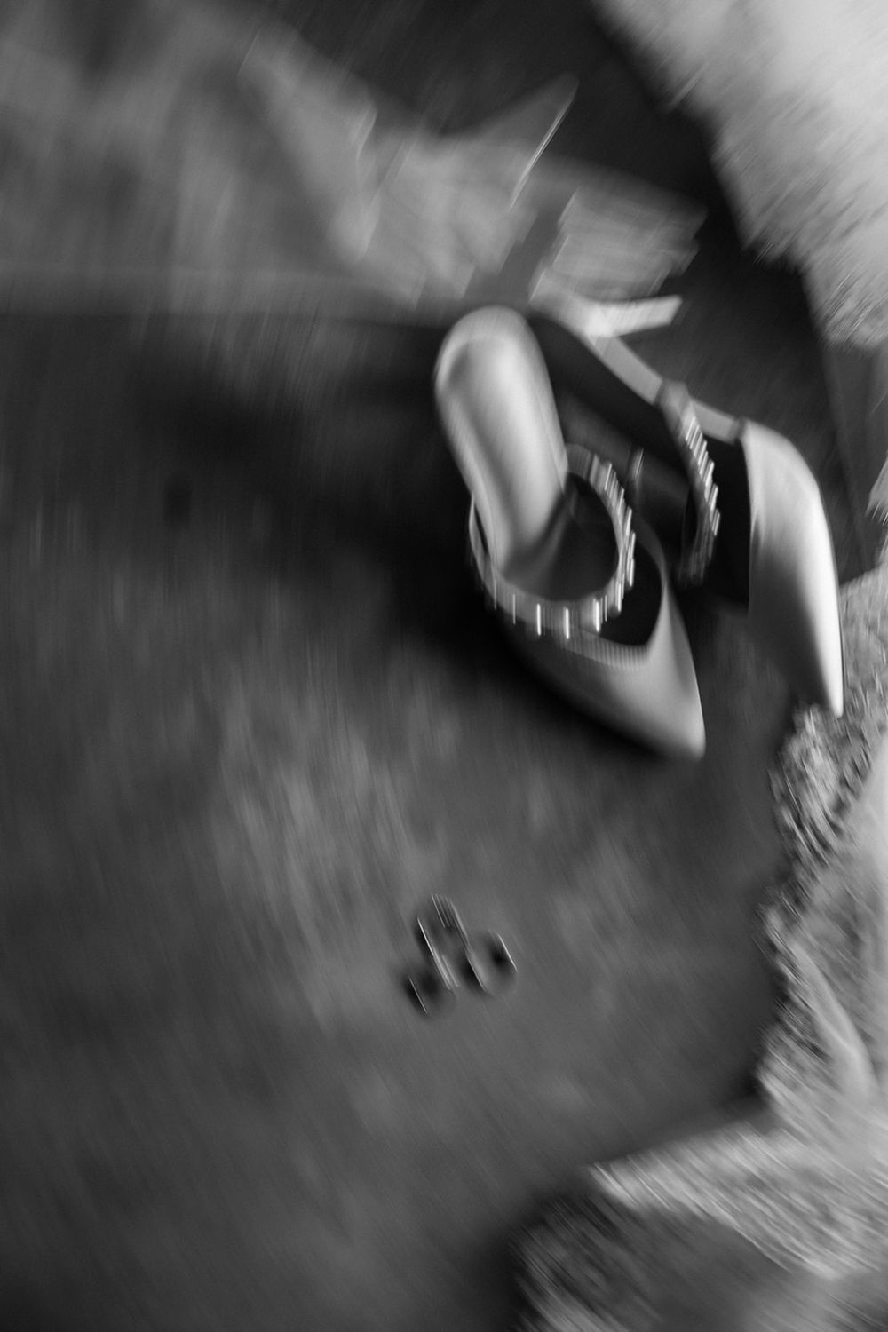 Artistic black and white motion blur photograph of a figure crouched low against a textured dark surface.