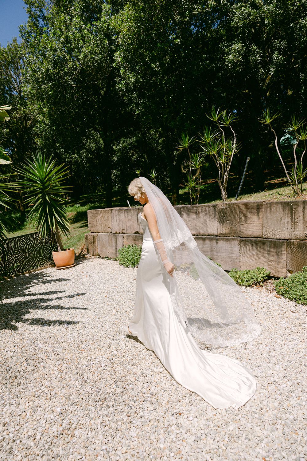 A bridal photo sequence showing flowing white wedding dress movement against a gravel garden backdrop with lush greenery.