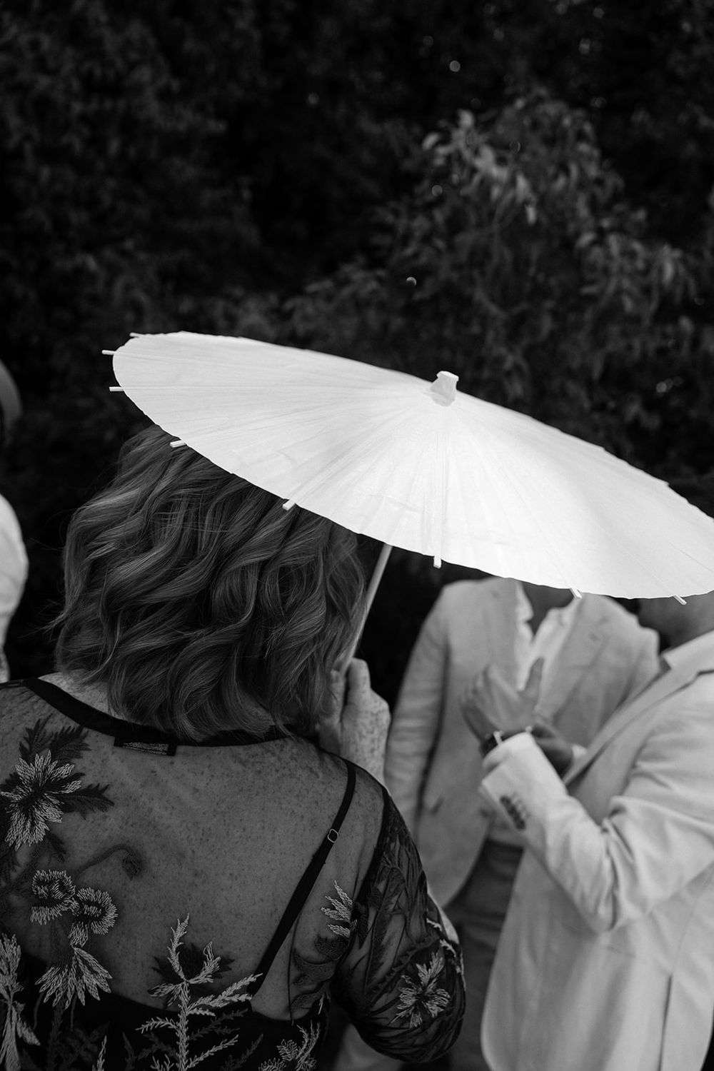 People carrying white paper parasols in a black and white artistic photograph.
