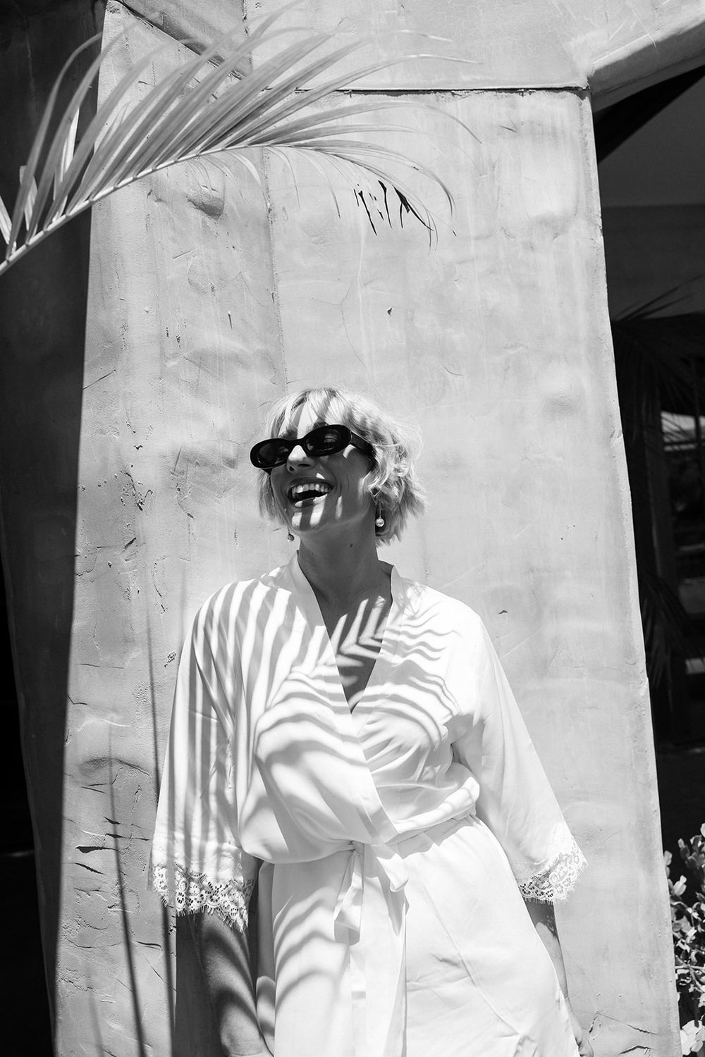 A black and white photo series showing someone in white clothing against a light-colored wall.