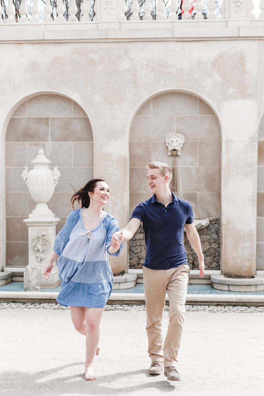 Joyful couple dancing and laughing together in an elegant stone courtyard with arches.