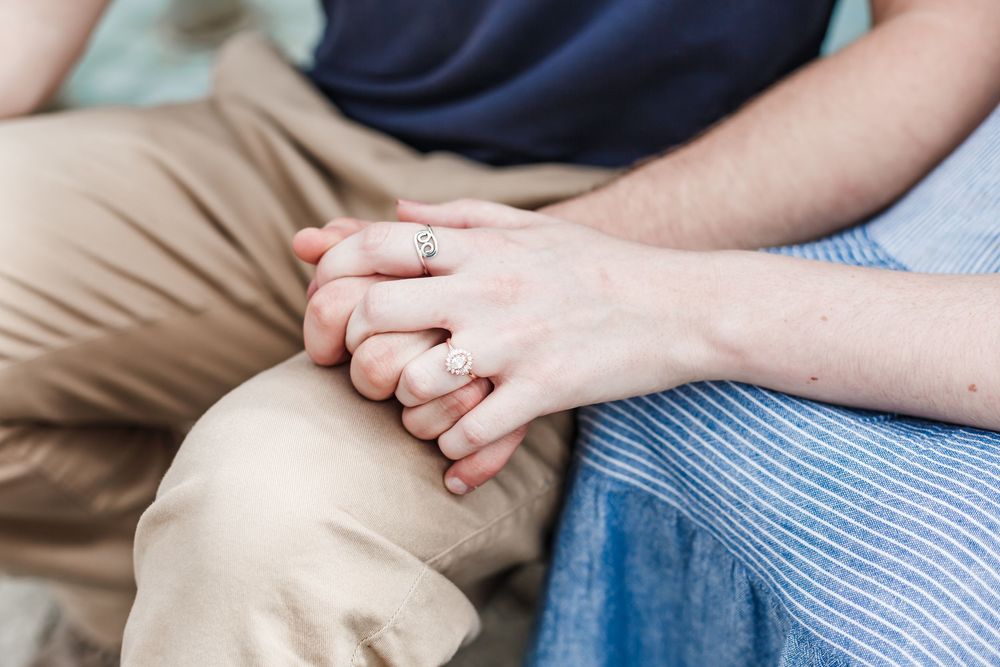 Close-up of intertwined hands resting on khaki pants and blue fabric.