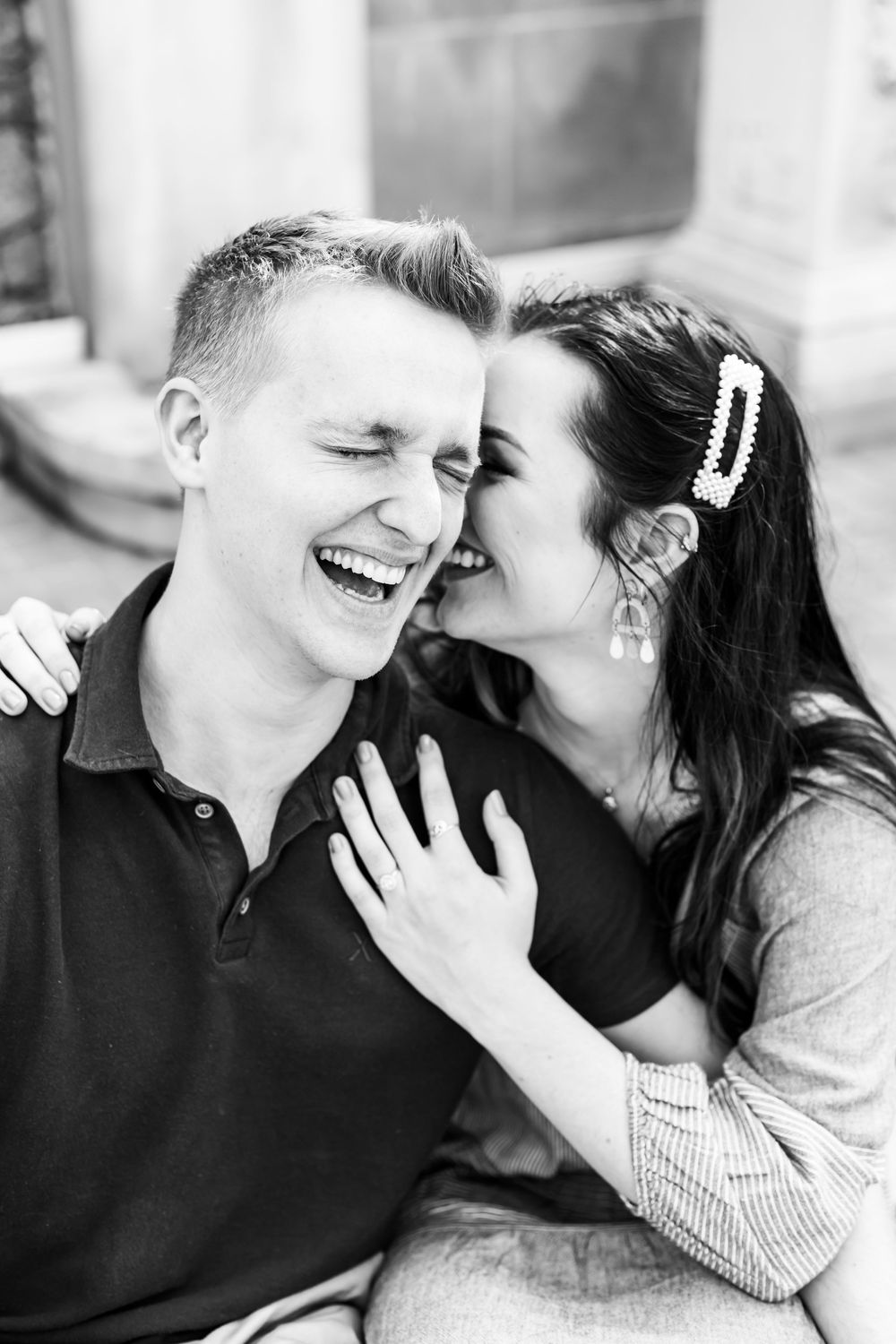 A candid black and white photo captures a joyful couple sharing an intimate laughing moment together.