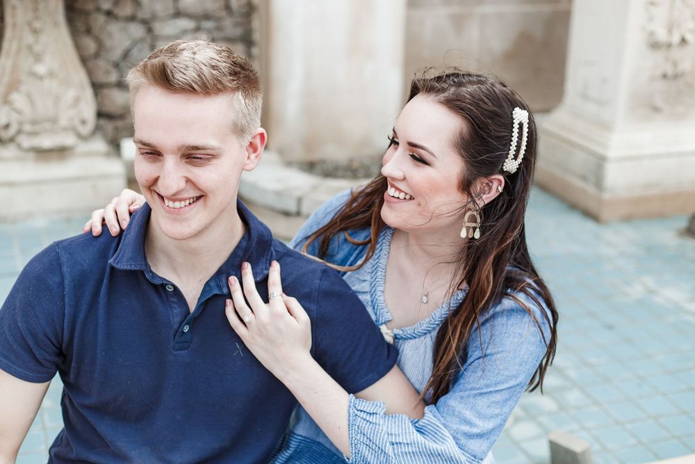 Laughing couple sharing tender moments by ornate stone architecture.