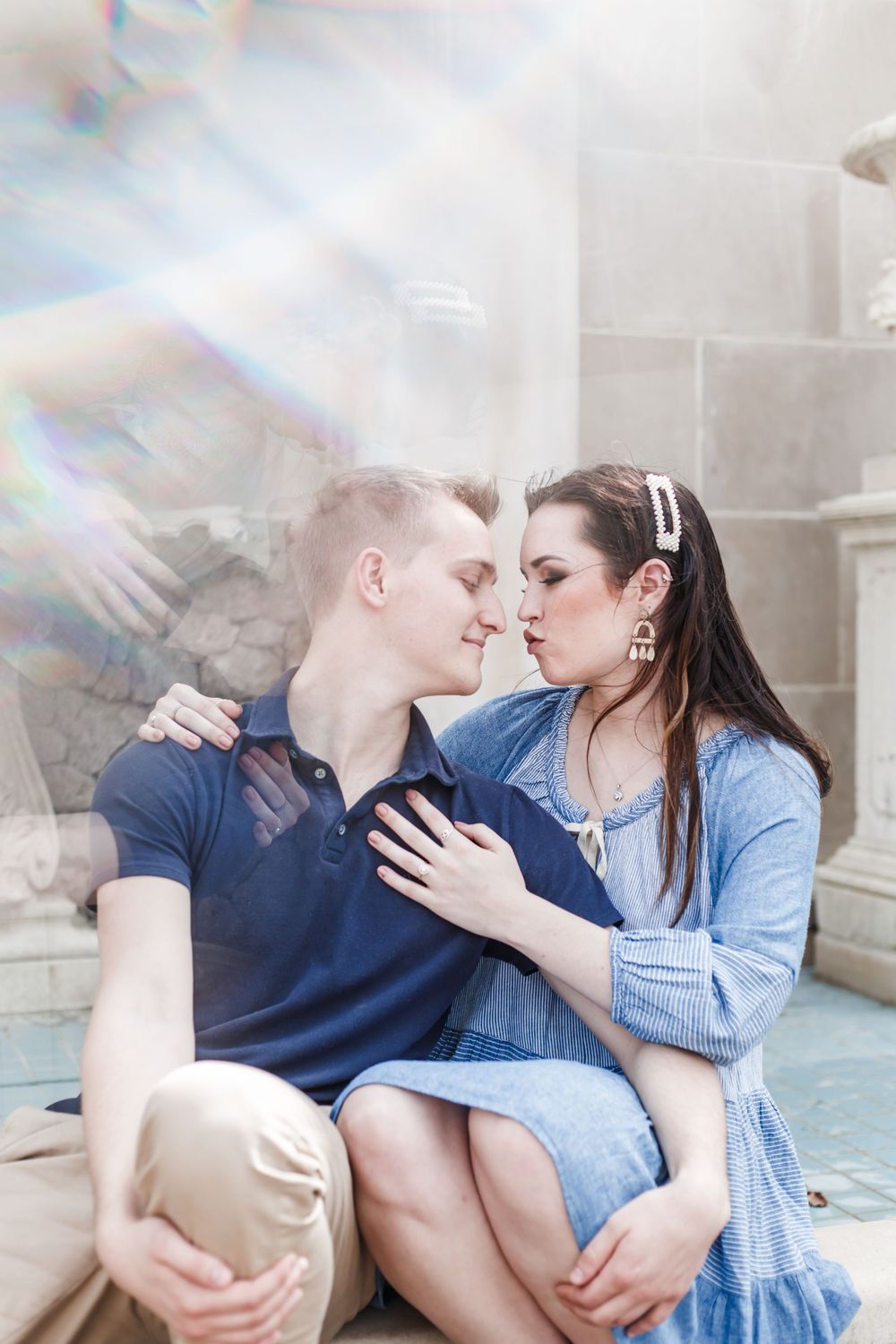 Romantic couple sharing an intimate moment on stone steps with dreamy lens flare.