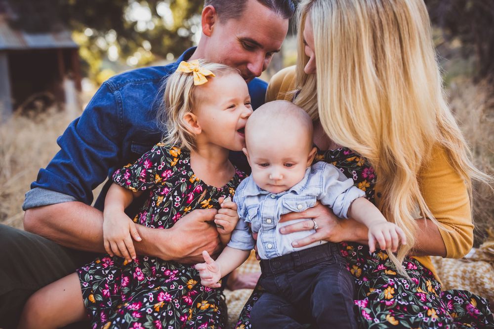 A loving family moment outdoors as they sit together and share smiles in matching floral outfits.