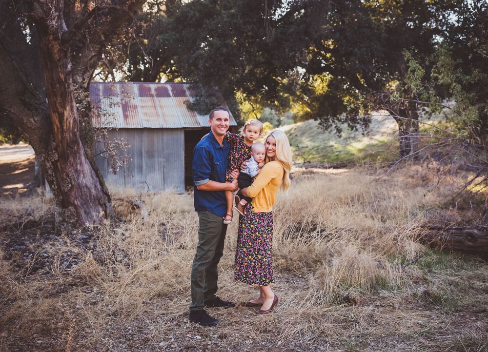 A couple takes outdoor engagement photos in a rustic autumn setting during golden hour.