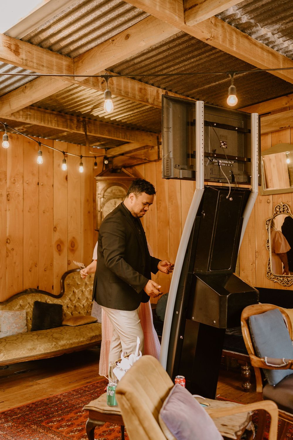 Interior setup scene with wooden beams and string lights in rustic venue space.