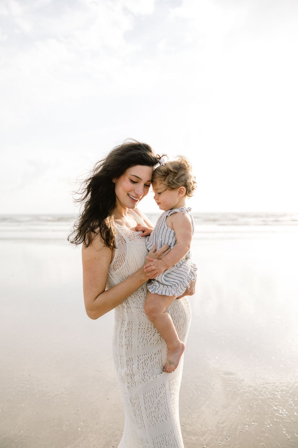 A heartwarming scene of maternal love captured on a misty beach.