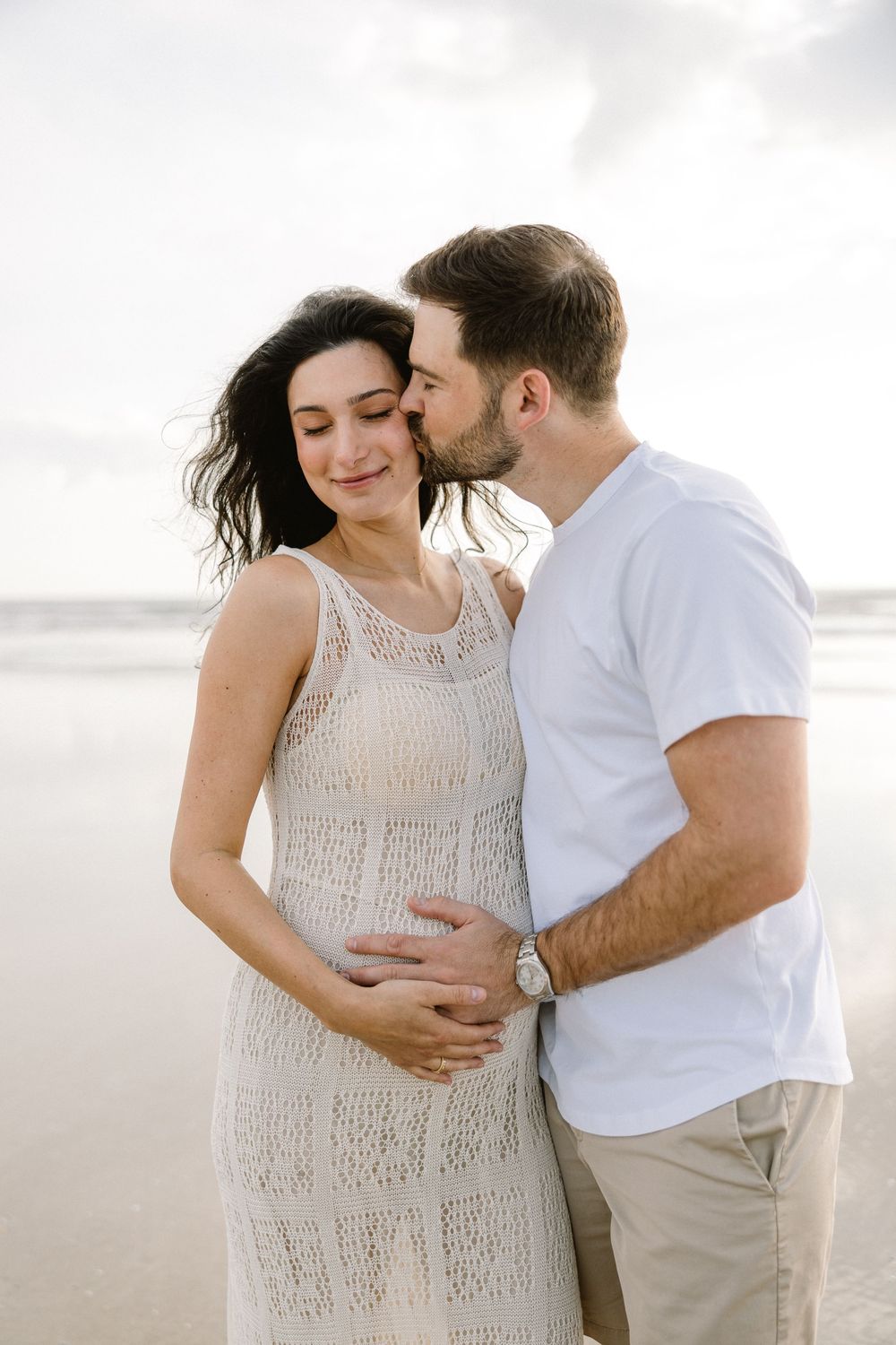 A romantic beach moment captured during a maternity photoshoot.