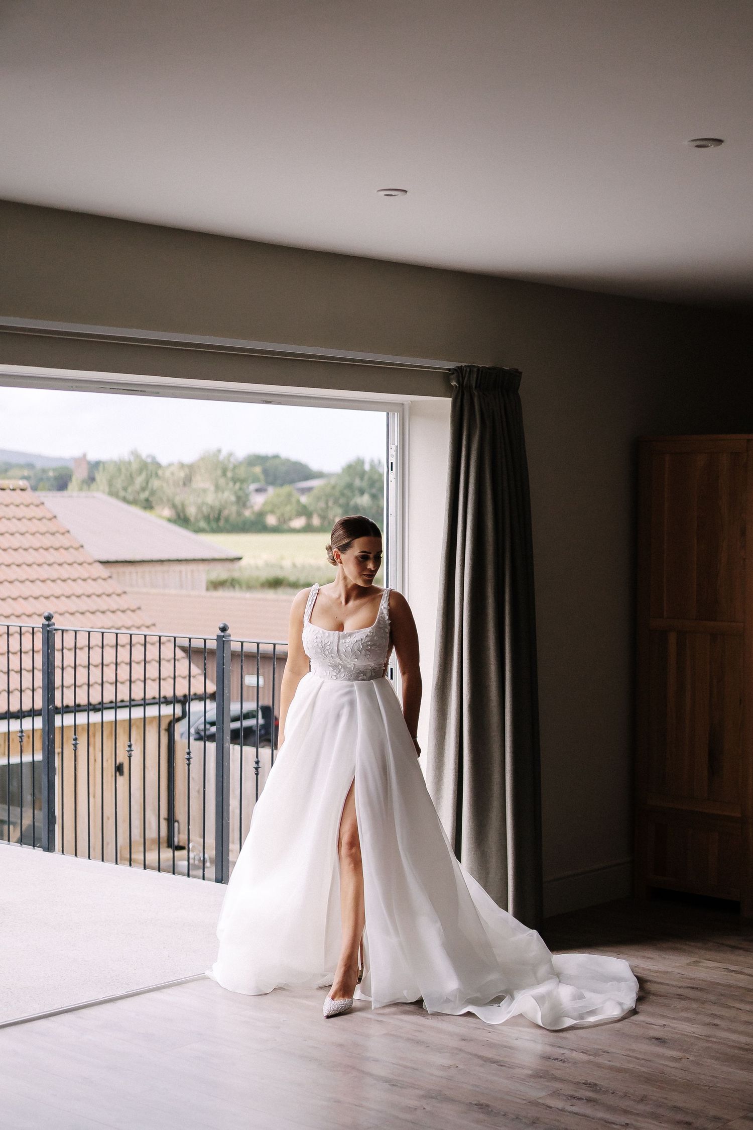 A series of black and white wedding dress preparation photos showing final adjustments and touches in a bright room.