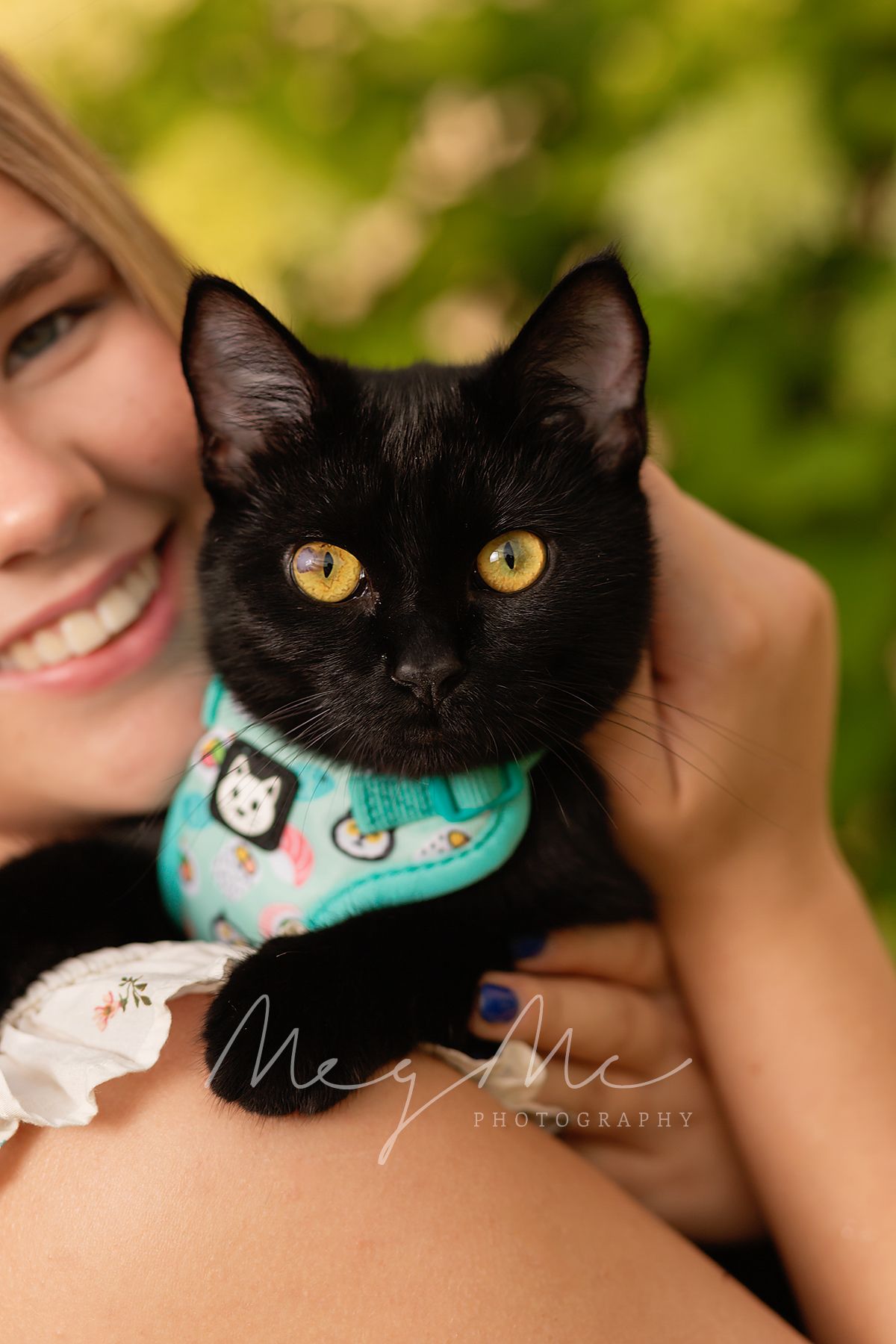 Teen holding black cat with bright yellow eyes wearing a turquoise bandana in senior picture session with MegMc Photography, Medina, TN