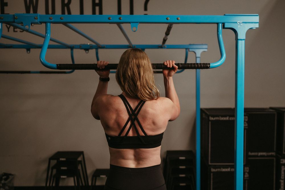 Person demonstrating correct form during a parallel bar dip exercise in a gym setting.