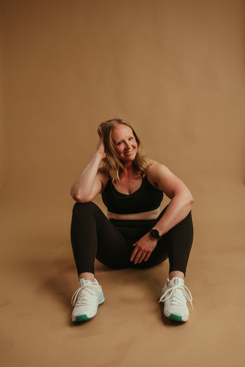 Person in black athletic wear sitting on floor against brown background showing four different relaxed poses.