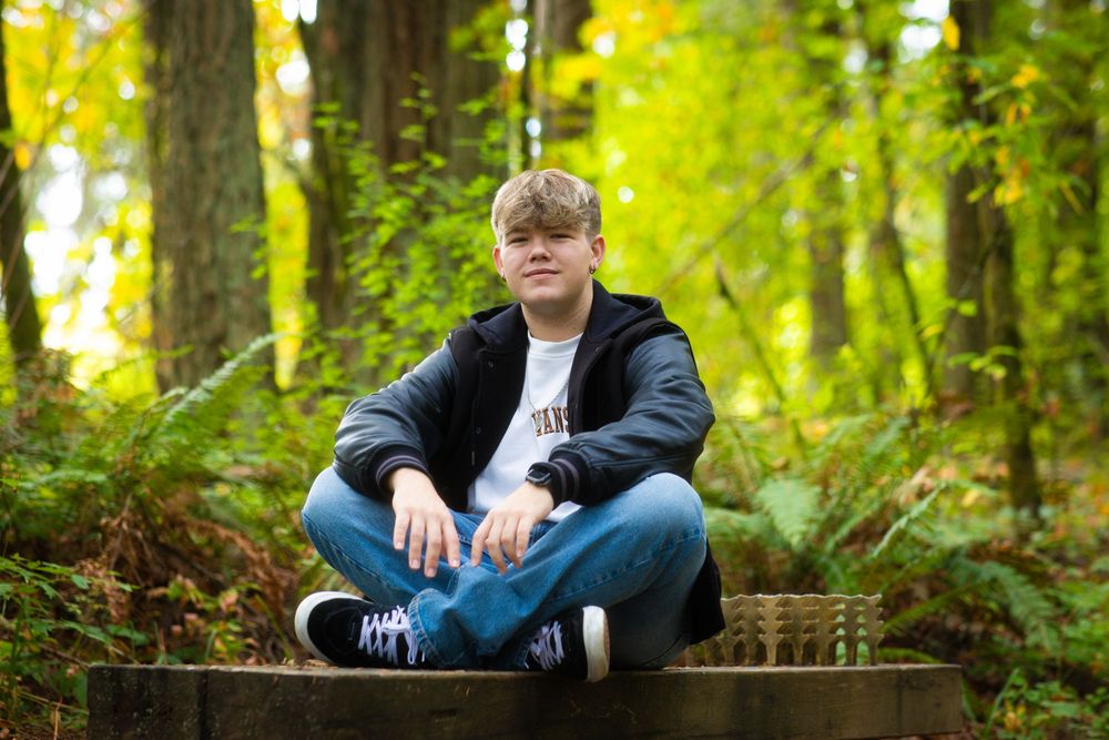 Person sits on rustic wooden steps in lush green forest during daytime.