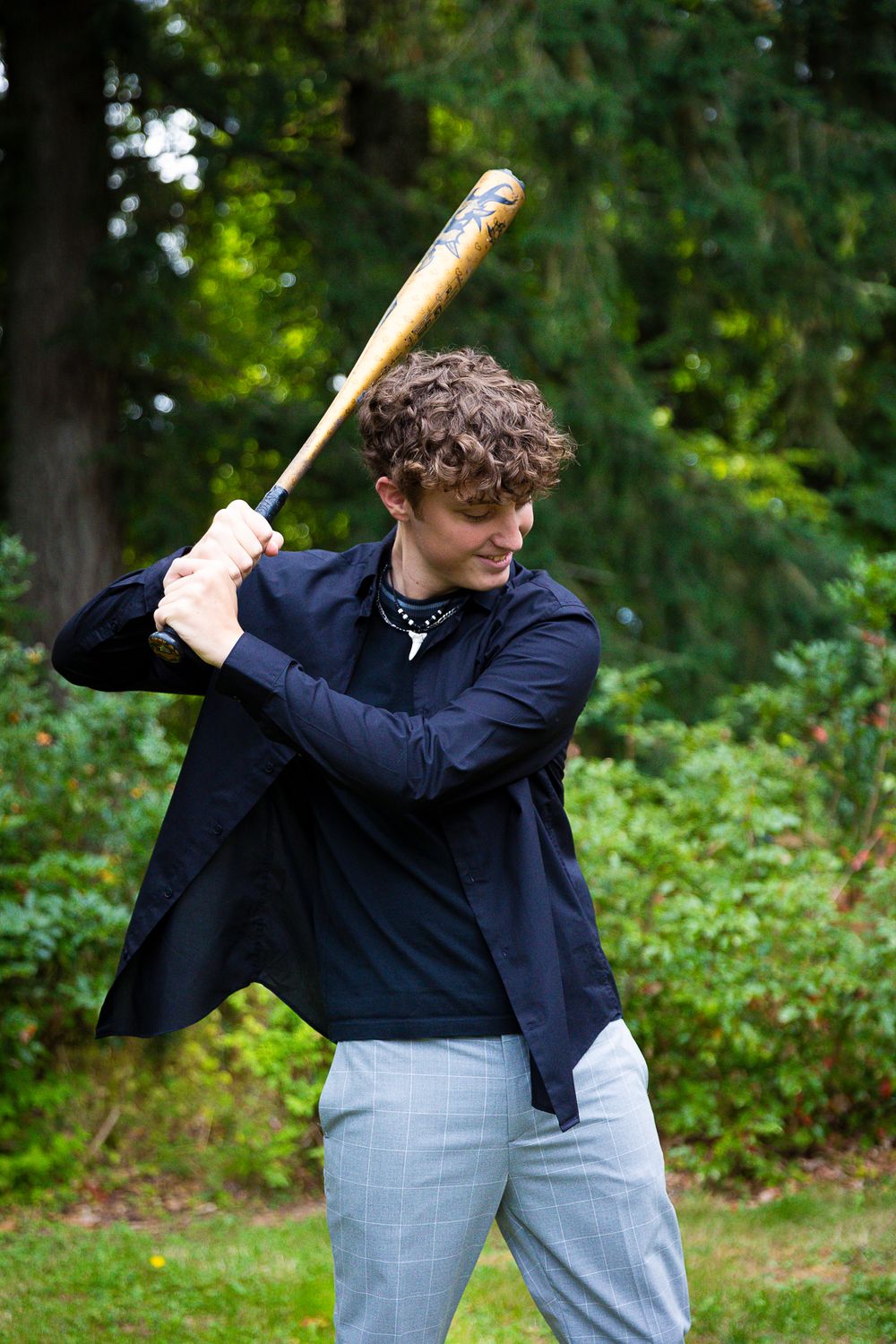 Baseball player practicing swing form in navy blue uniform outdoors.