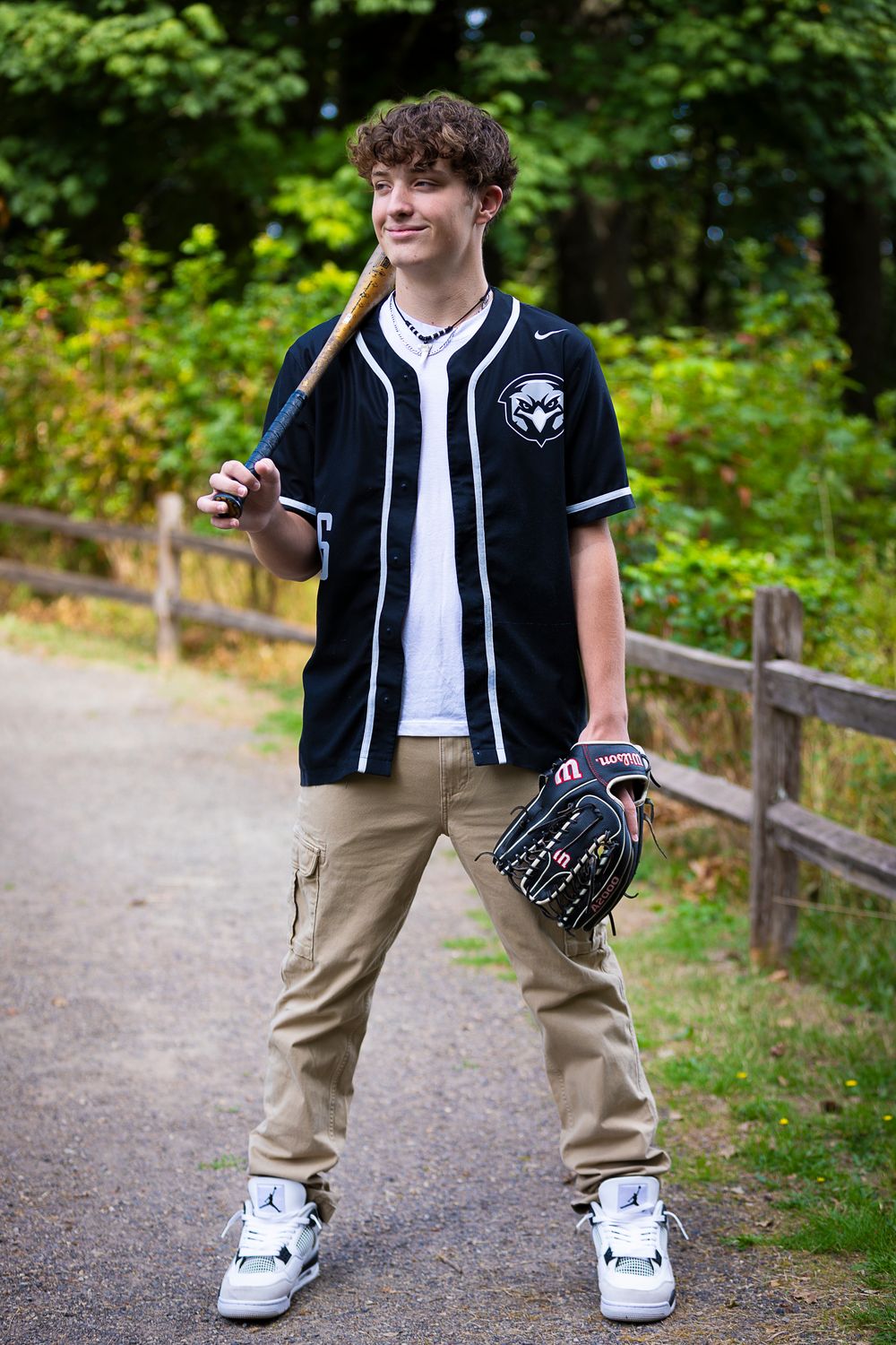 Baseball player in uniform showing fielding stance with glove on path.