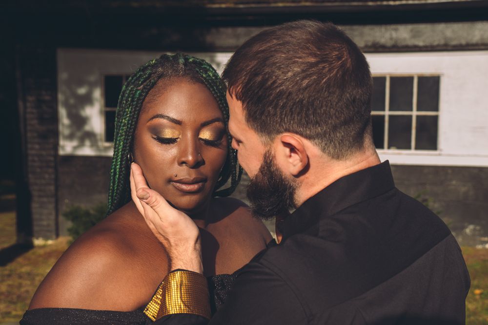 A tender moment between a couple in formal attire against a classic architectural backdrop.