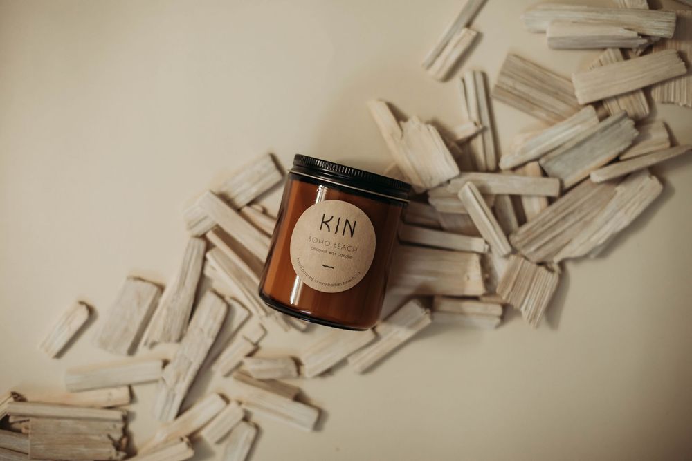 Brown glass jar labeled Jin sits atop scattered white wooden clothespins on a cream colored surface.