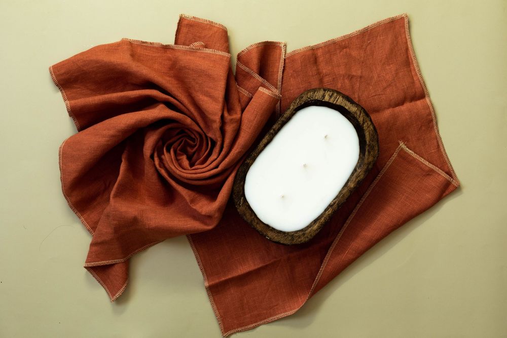 Small oval vanity mirror surrounded by draped rust-colored velvet fabric on beige surface.