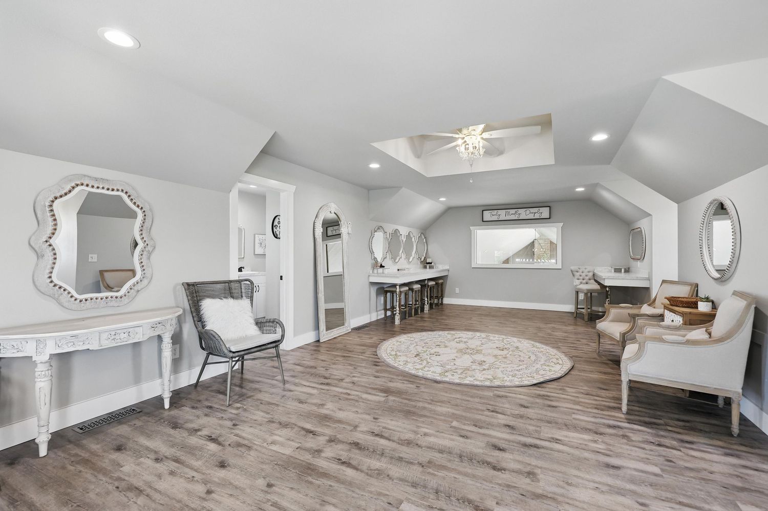 Elegant attic living space with gray walls, hardwood floors, decorative mirrors, and modern white furniture.