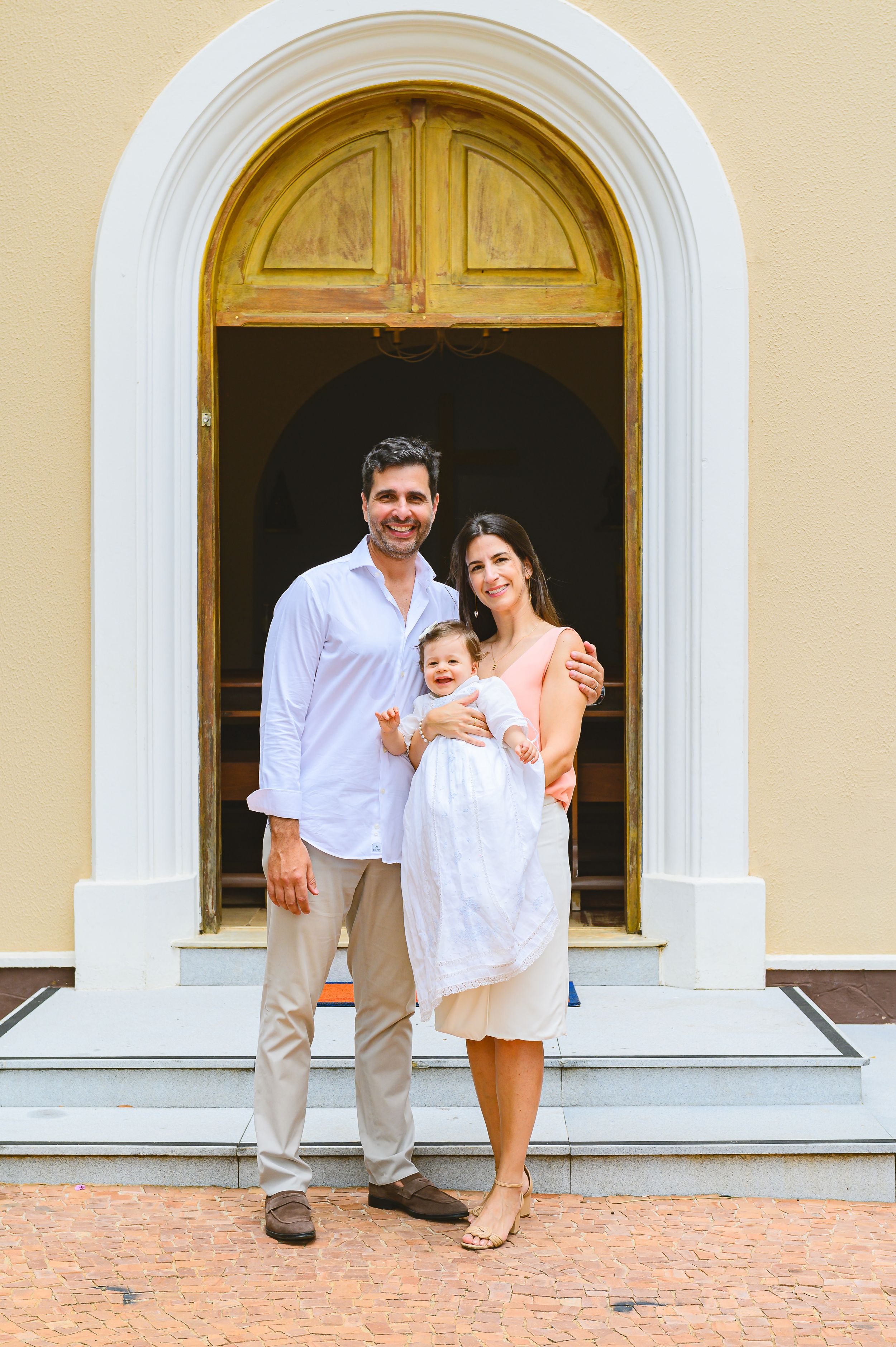 A family stands together in a grand arched doorway of a church or historic building with yellow walls and terracotta flooring.