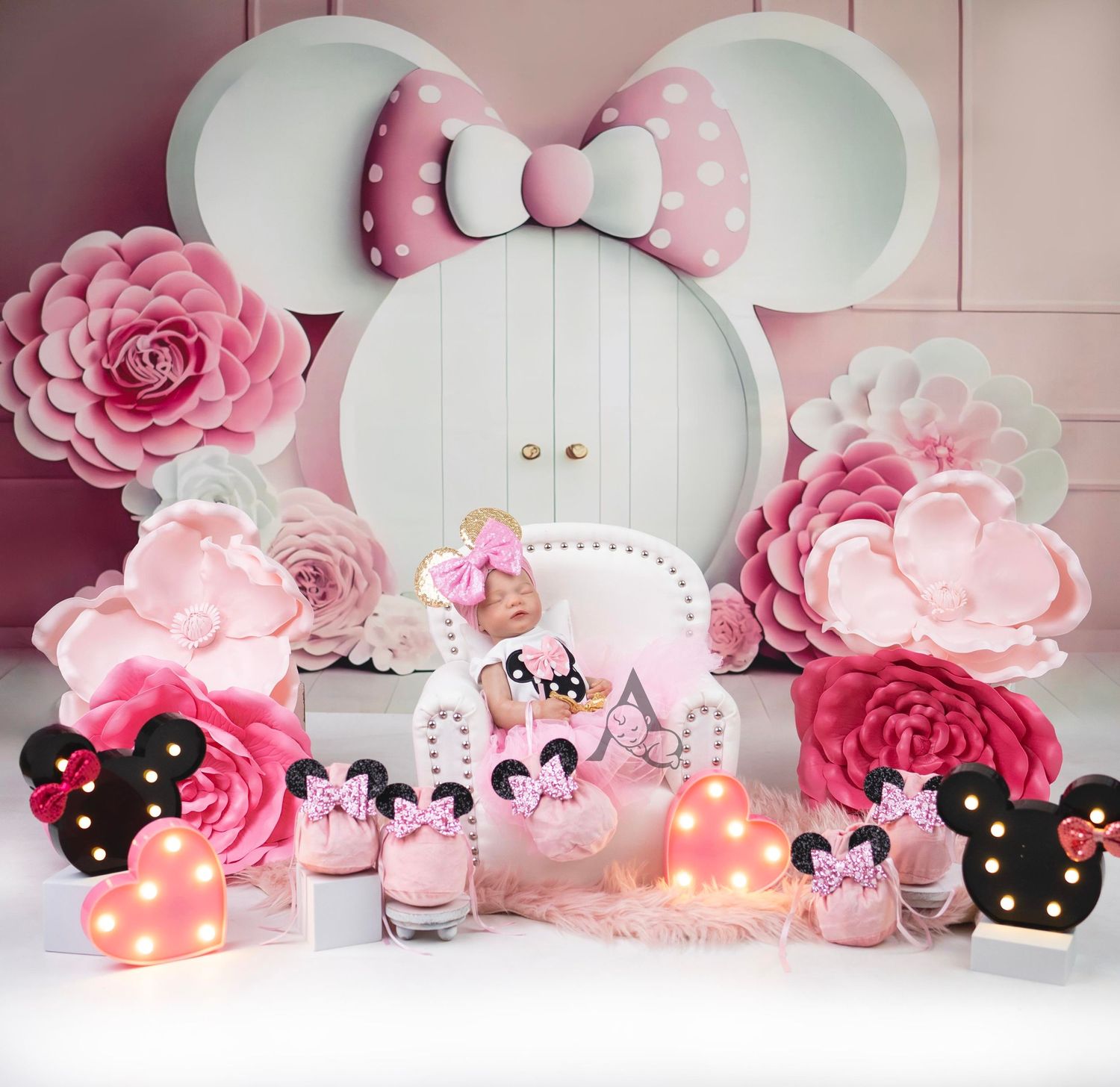 Pink Minnie Mouse themed backdrop with floral decorations and illuminated accessories.