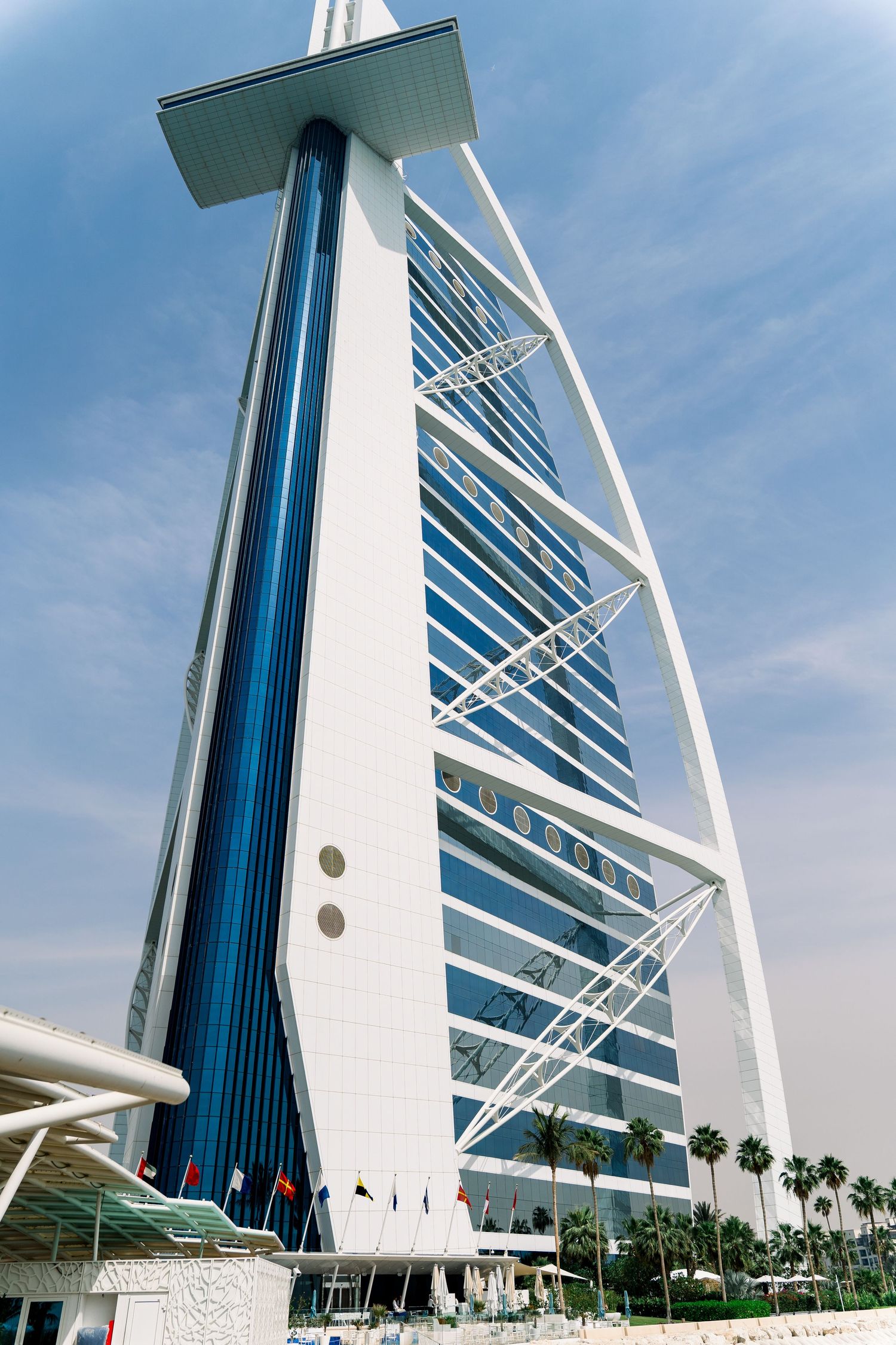 The iconic Burj Al Arab luxury hotel rises against a blue sky in Dubai, showcasing its distinctive sail-shaped architecture.