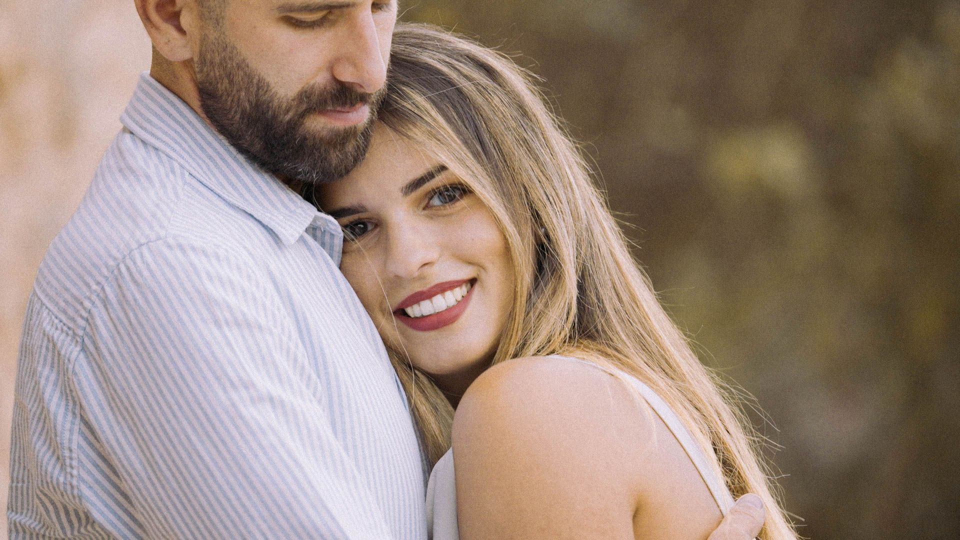 Close up portrait of a loving couple embracing outdoors with a gentle sunset glow in the background.
