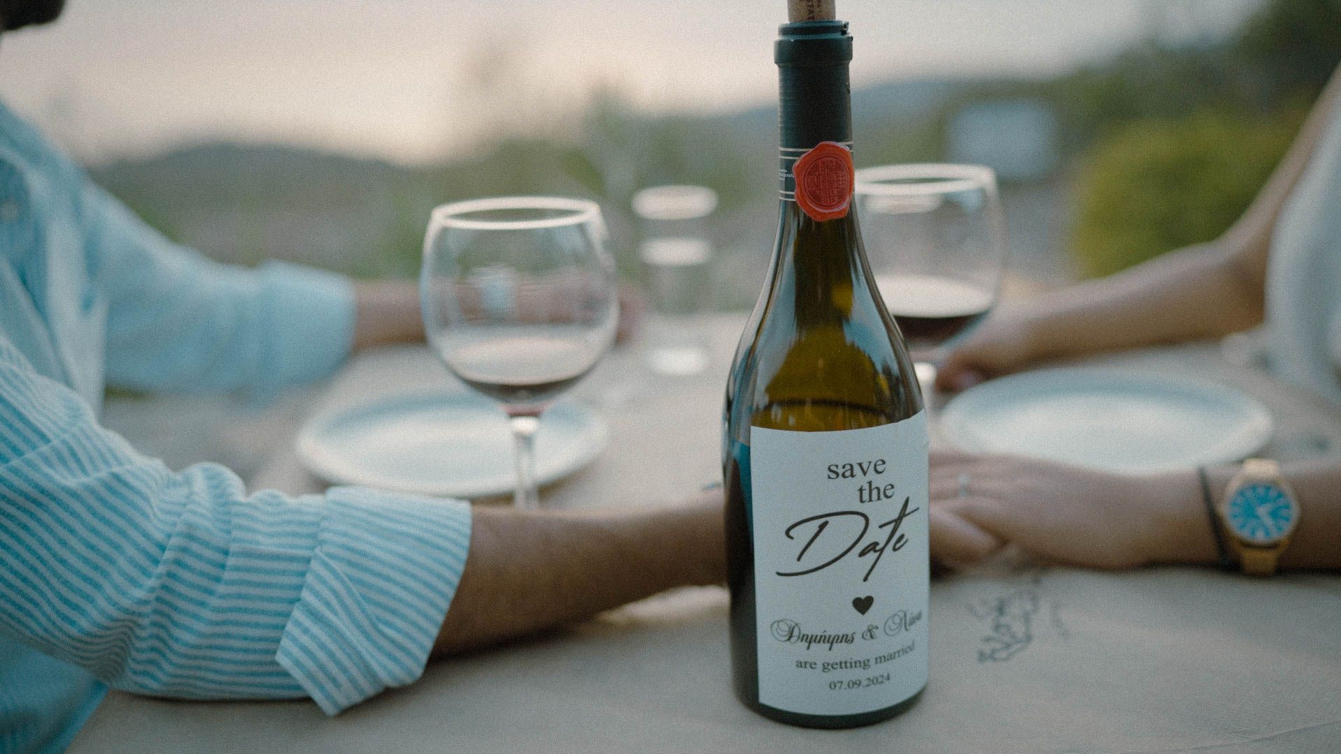Wine bottle and empty glasses at an outdoor table setting during golden hour sunset.