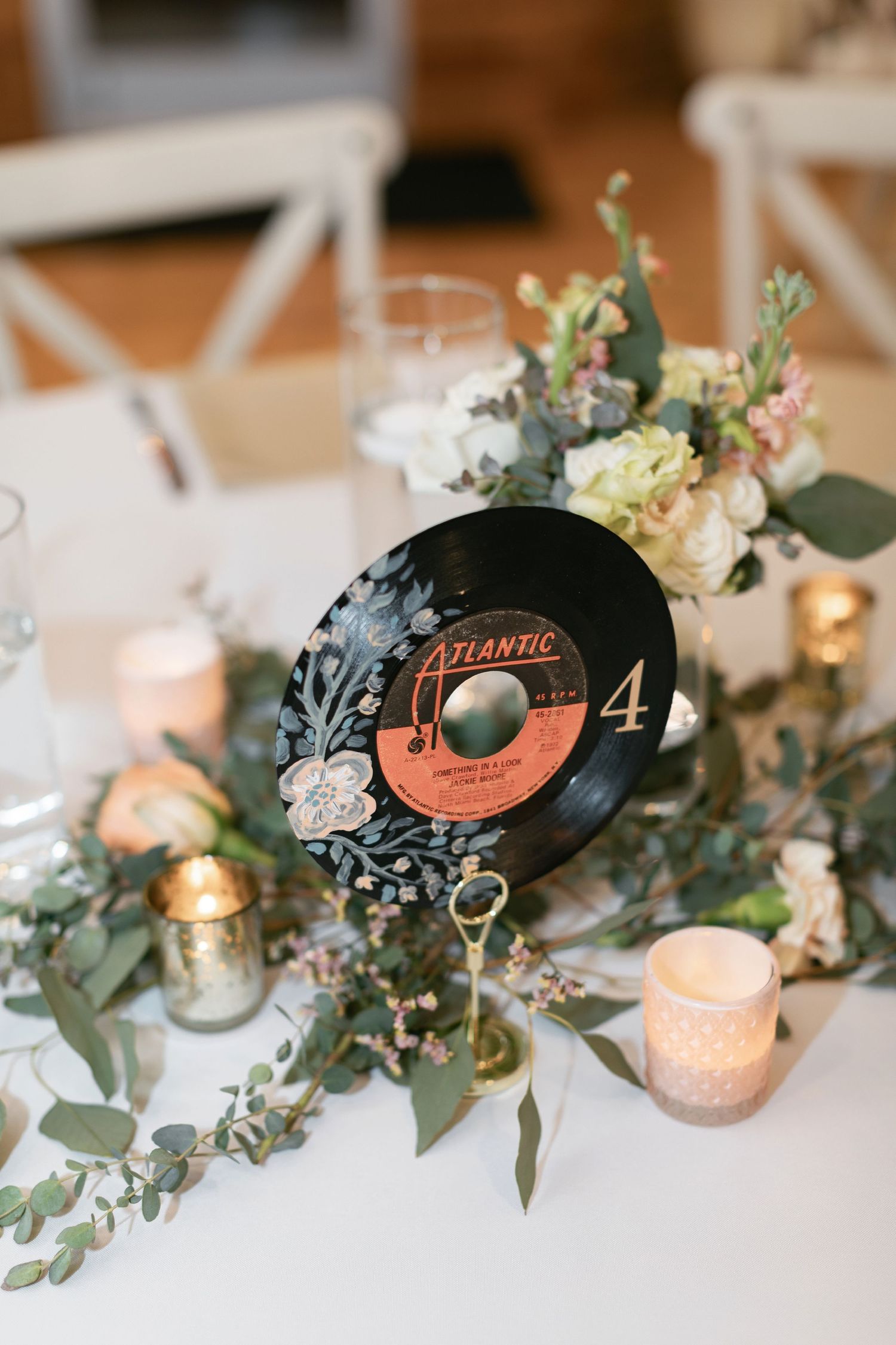 A vintage vinyl record serves as a wedding table number with candles and eucalyptus garland centerpiece decoration for a Nashville wedding.