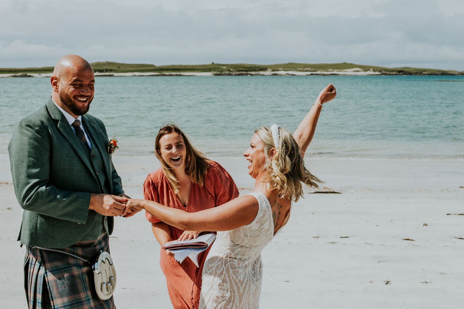 A joyful celebration on a beach with people dancing and laughing together.