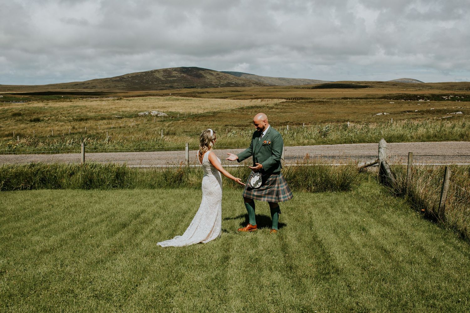 A traditional Scottish wedding celebration on rolling green hills with moody cloudy skies in the background.