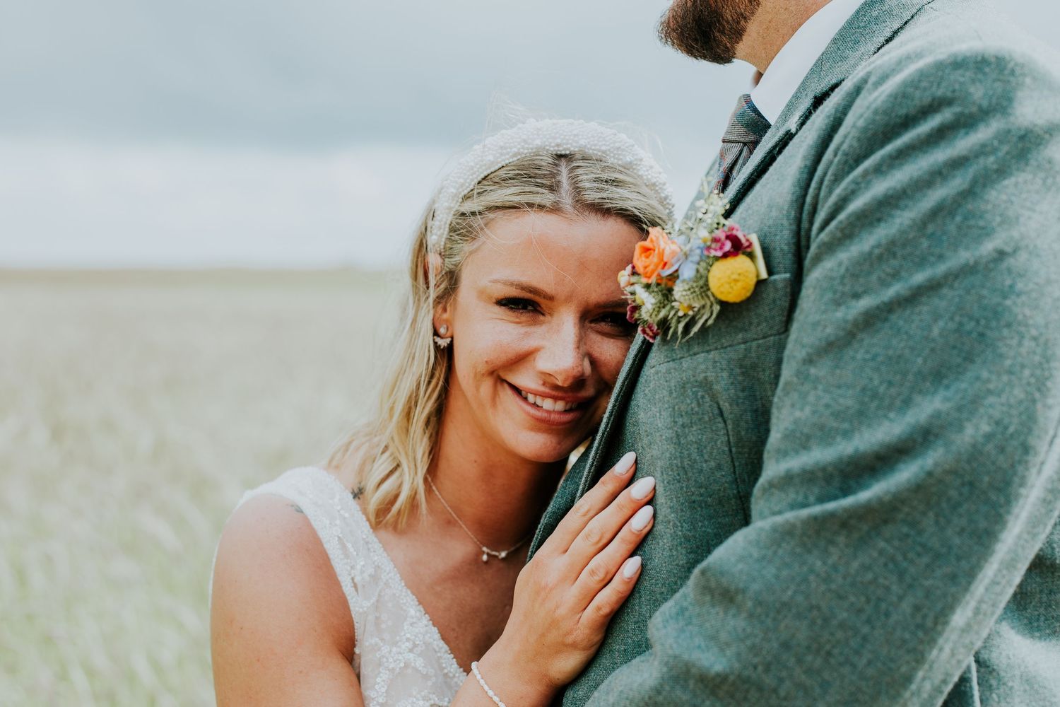 Close up of loving wedding couple embracing against scenic coastal background.
