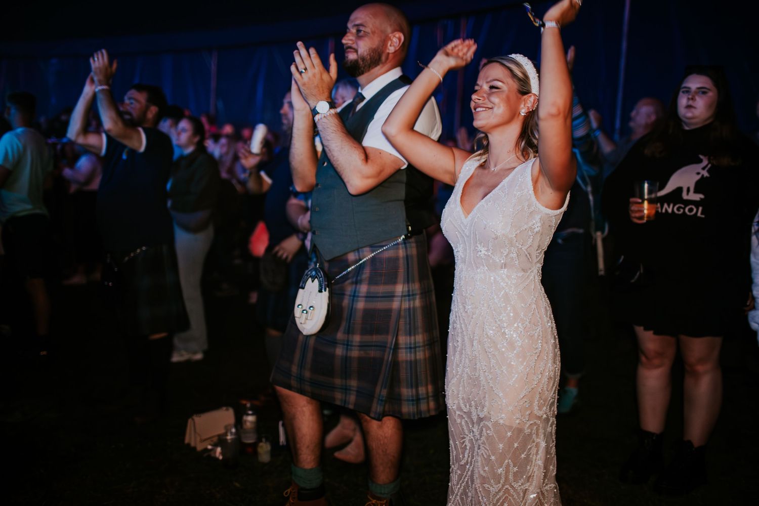 A couple dances and celebrates at their wedding reception, with the groom wearing a traditional kilt.
