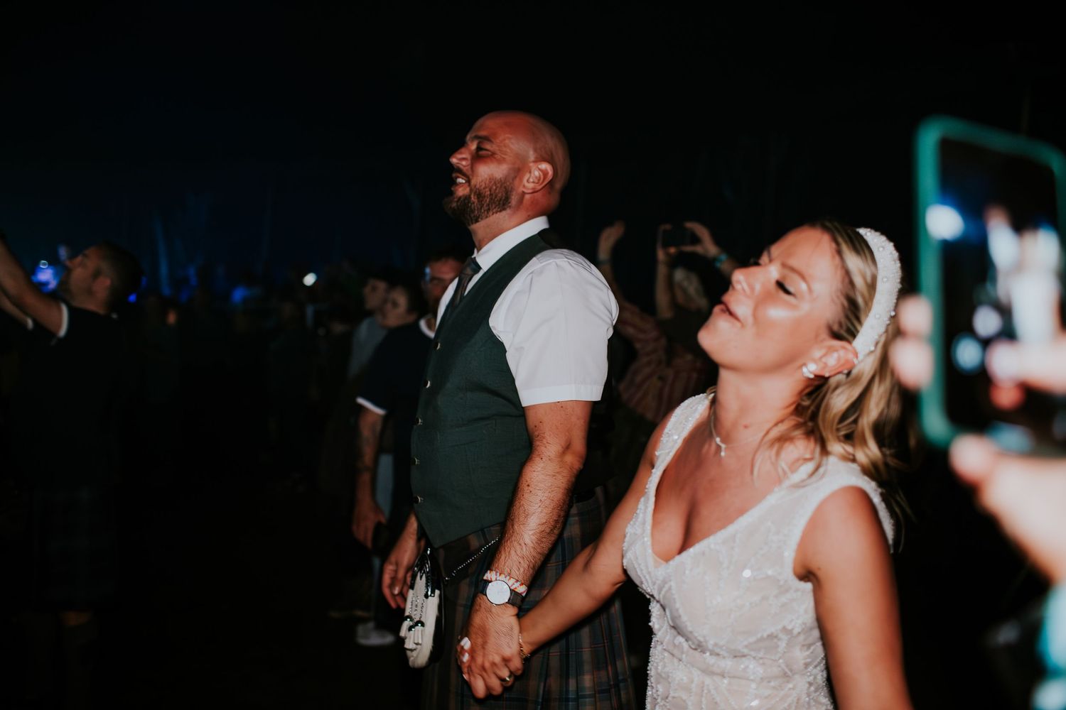 A couple enjoying themselves at a nighttime event with dramatic lighting and a festive atmosphere.