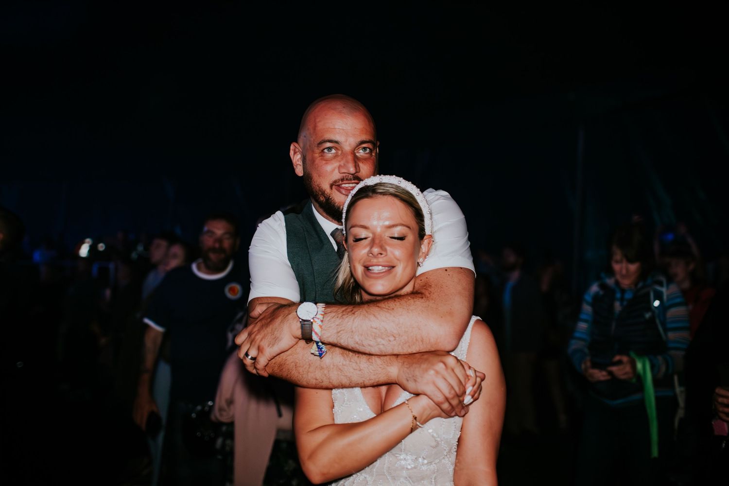 A couple sharing an intimate moment on a dance floor during what appears to be a wedding reception.