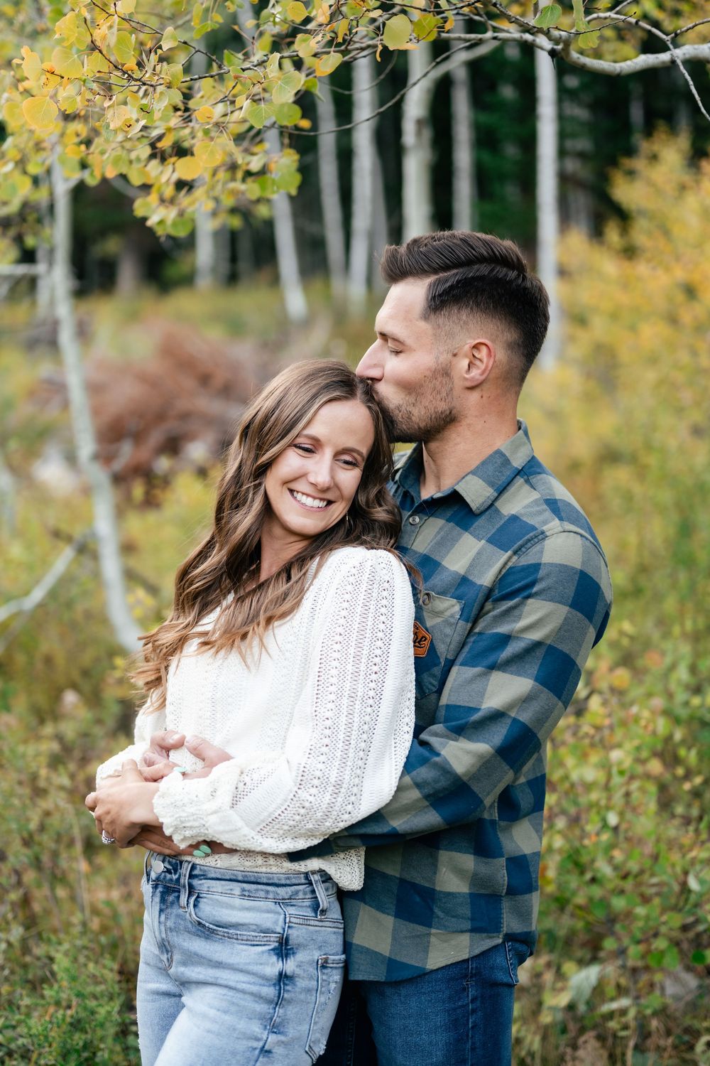 A loving moment shared between a couple among golden aspen trees in autumn.
