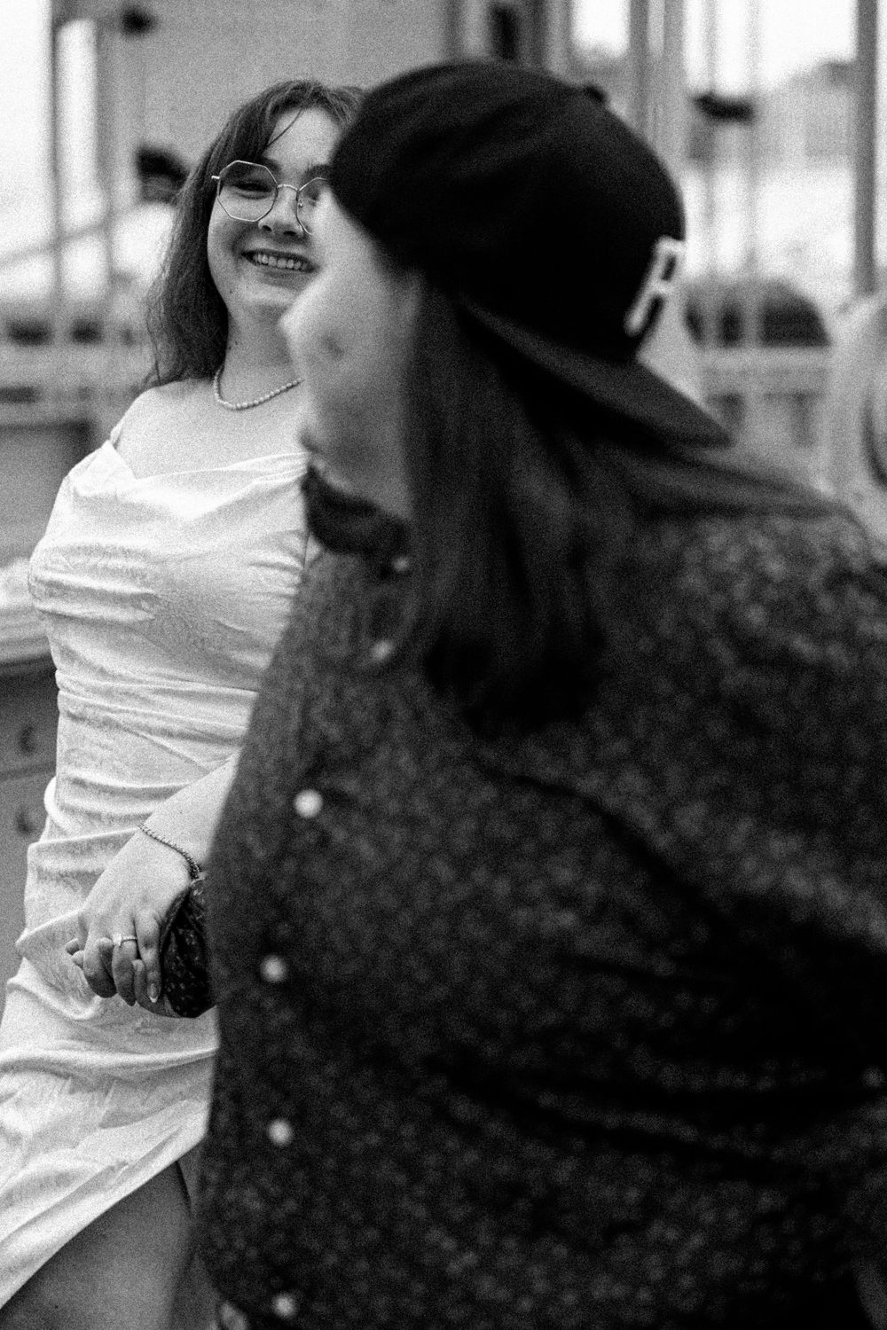Black and white candid photo showing two people conversing, one wearing white and one in polka dots having a joyful moment.