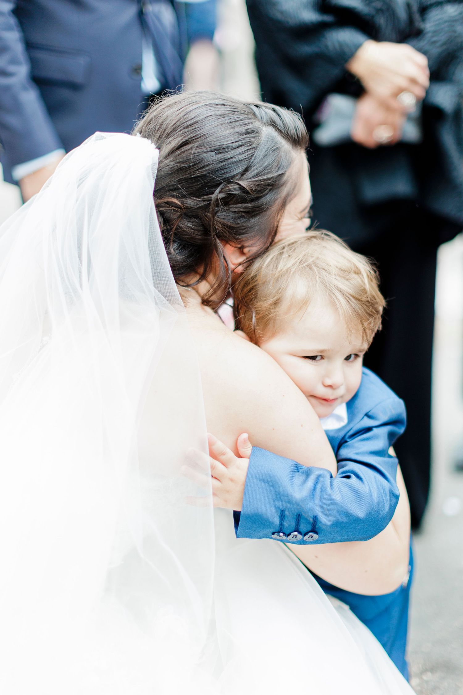 A touching moment between a bride in white and a small child in blue.