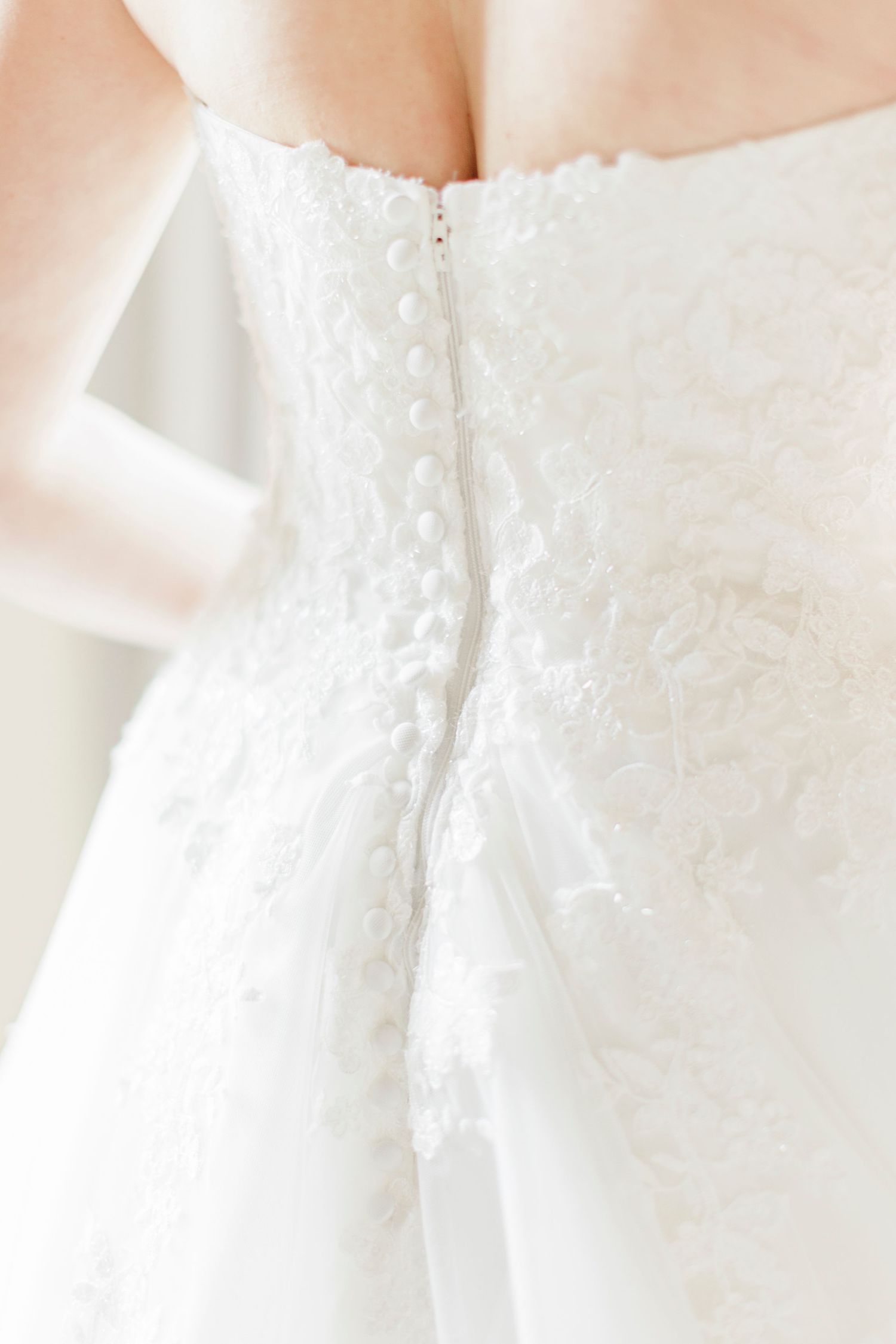 Close-up of the delicate lace and button details on the back of an elegant white wedding dress, captured at Domaine des Gaillardoux