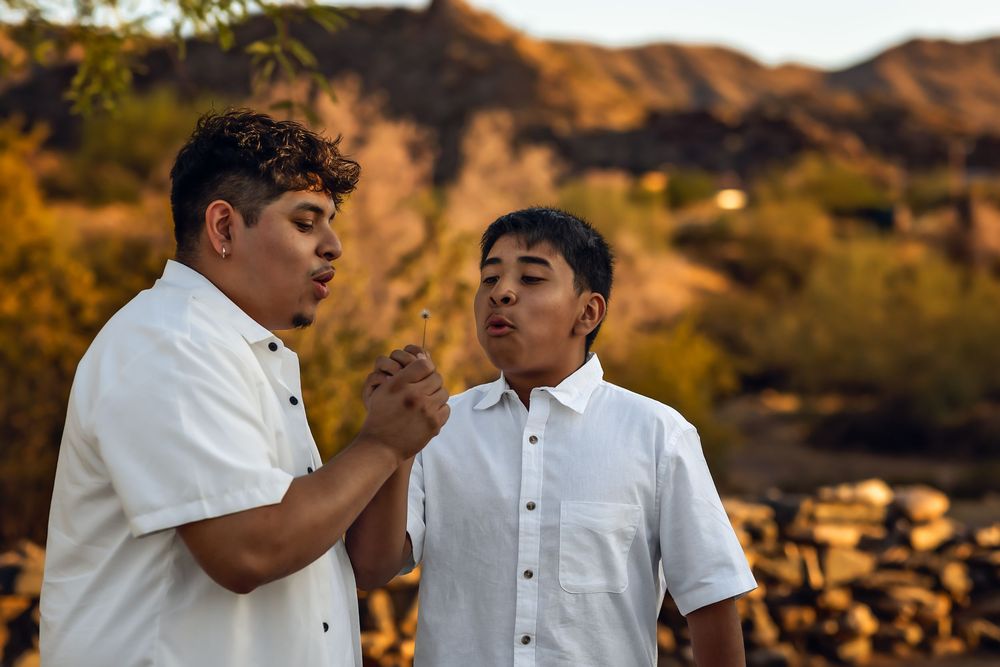 Two people in white button-up shirts having a conversation against a desert mountain backdrop at golden hour.