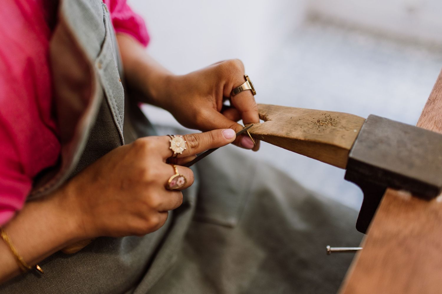 Close-up of hands working with metalworking tools during jewelry creation.