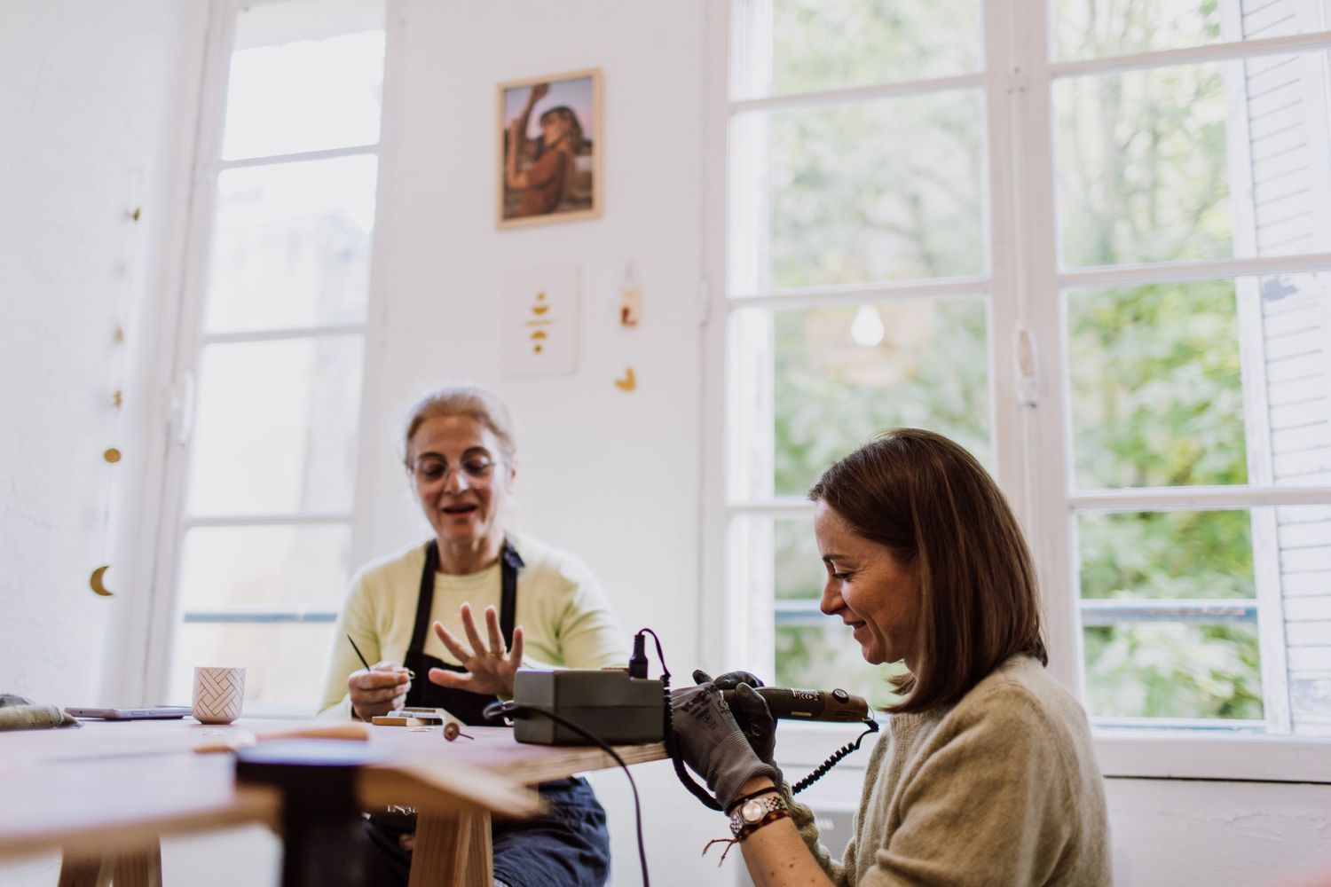 Two people share a lighthearted moment while working on jewelry projects.