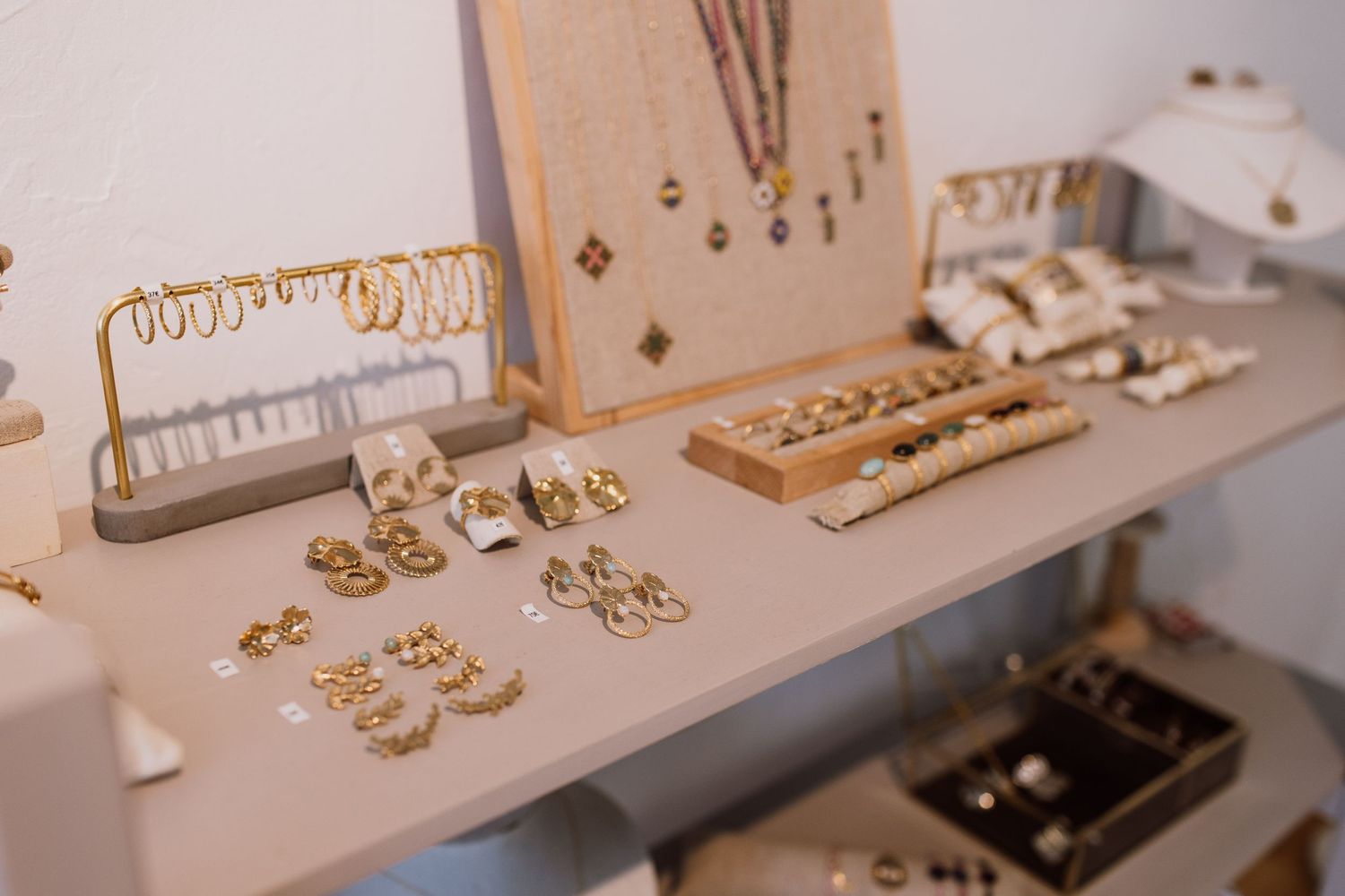Organized display of handmade jewelry pieces and crafting materials on light colored surface.