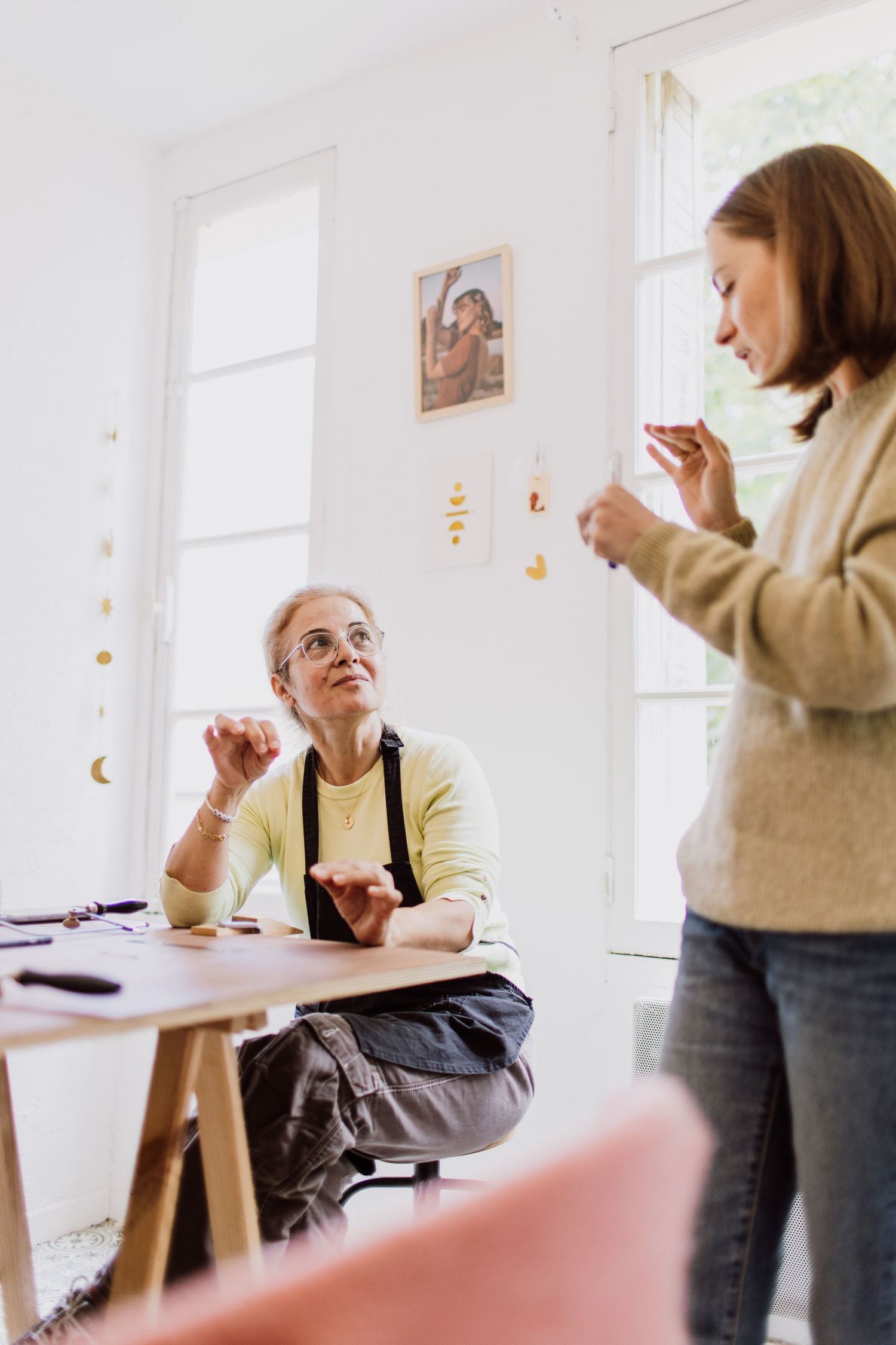 Casual crafting meetup in bright white room with natural light streaming through windows.