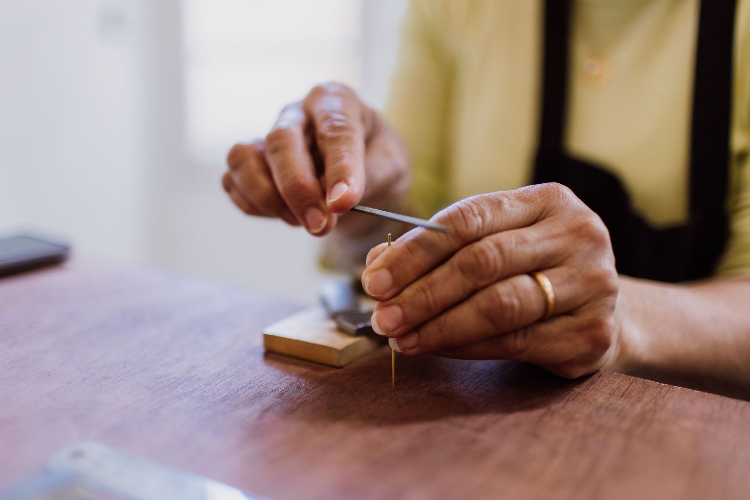 Close-up of hands working on small craft project on wooden surface.