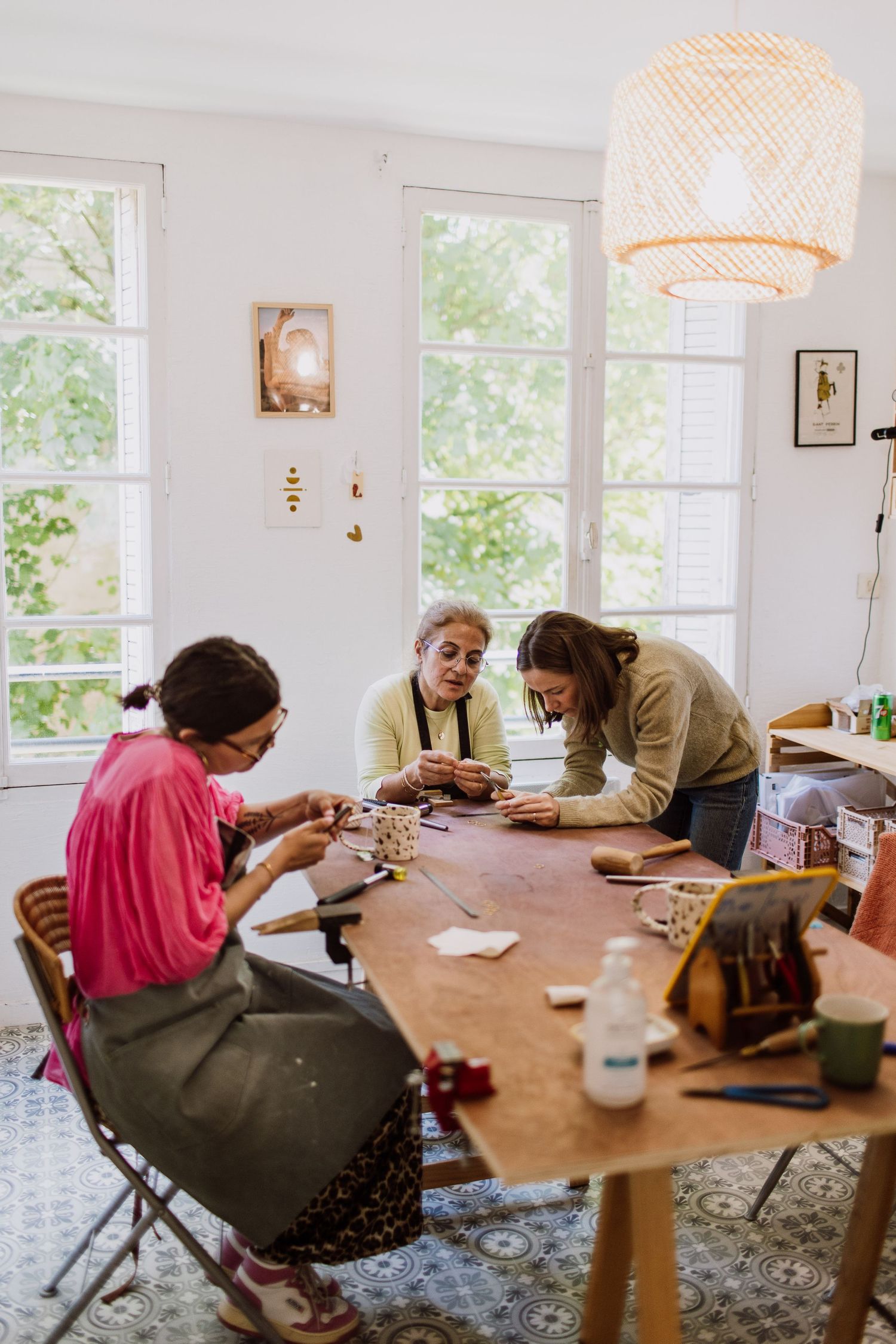 Craft workshop in progress at wooden table under woven pendant light.