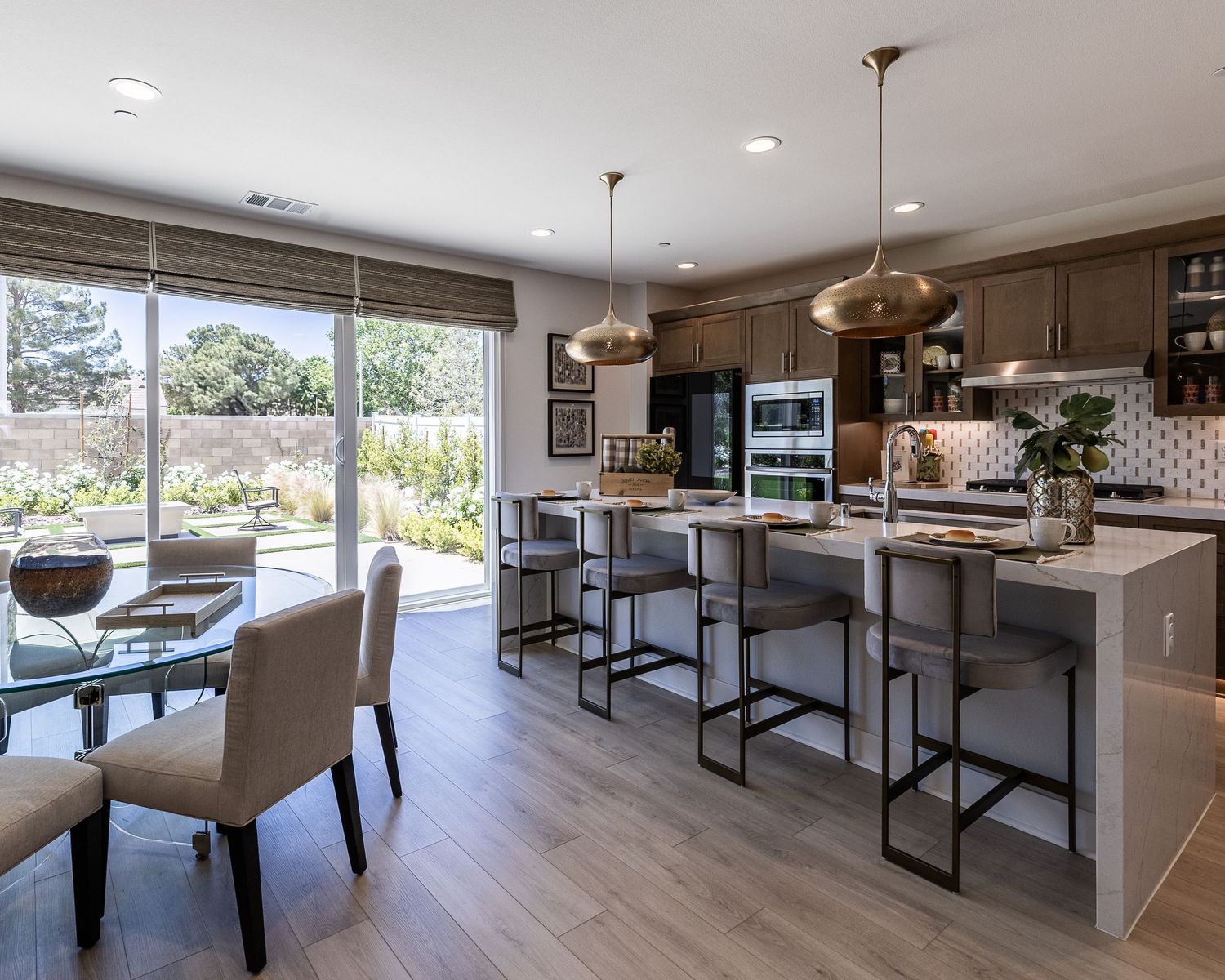 Modern kitchen and dining area with quartz countertops, pendant lighting, and tall bar stools overlooking backyard views in Palmdale CA.